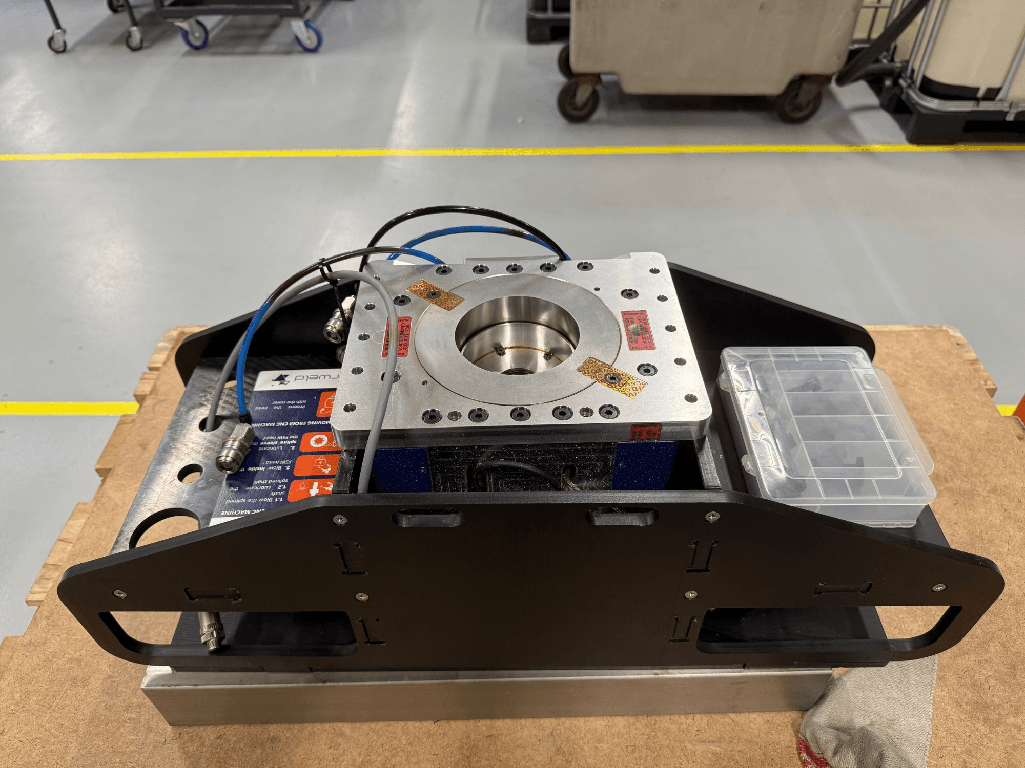 Componente metálico mecanizado con cables azules, caja de accesorios y base plana, mostrado desde arriba, ideal para aplicaciones mecánicas.