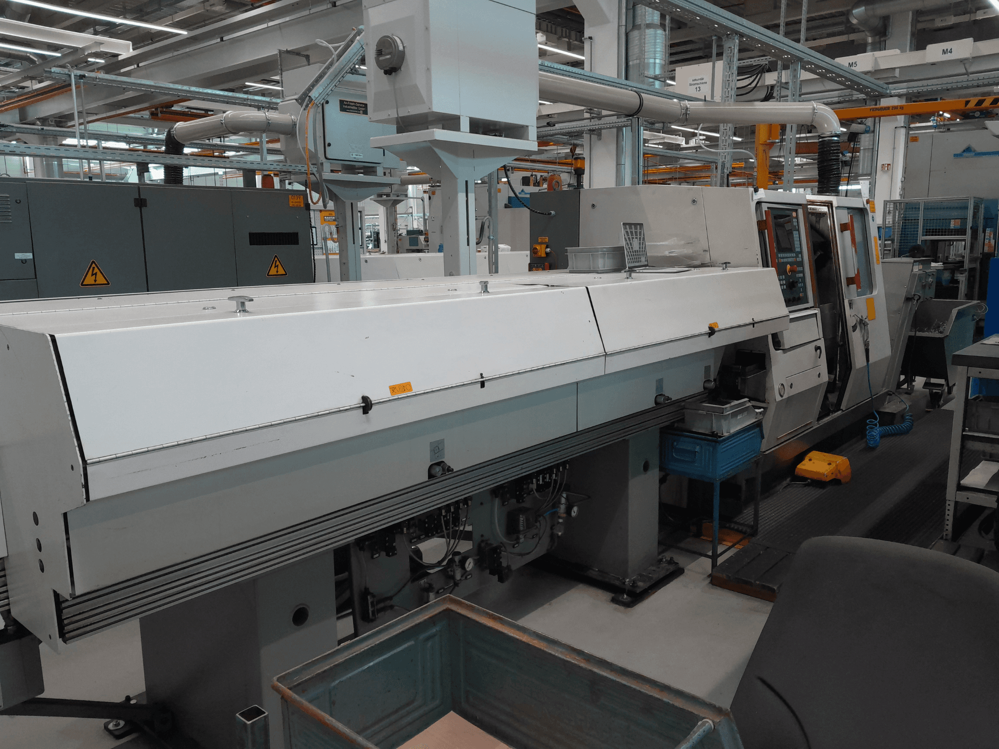 Máquina de torneado horizontal TRAUB TNA 300, vista frontal; presenta un diseño elegante, panel de control y espacio de trabajo operativo.