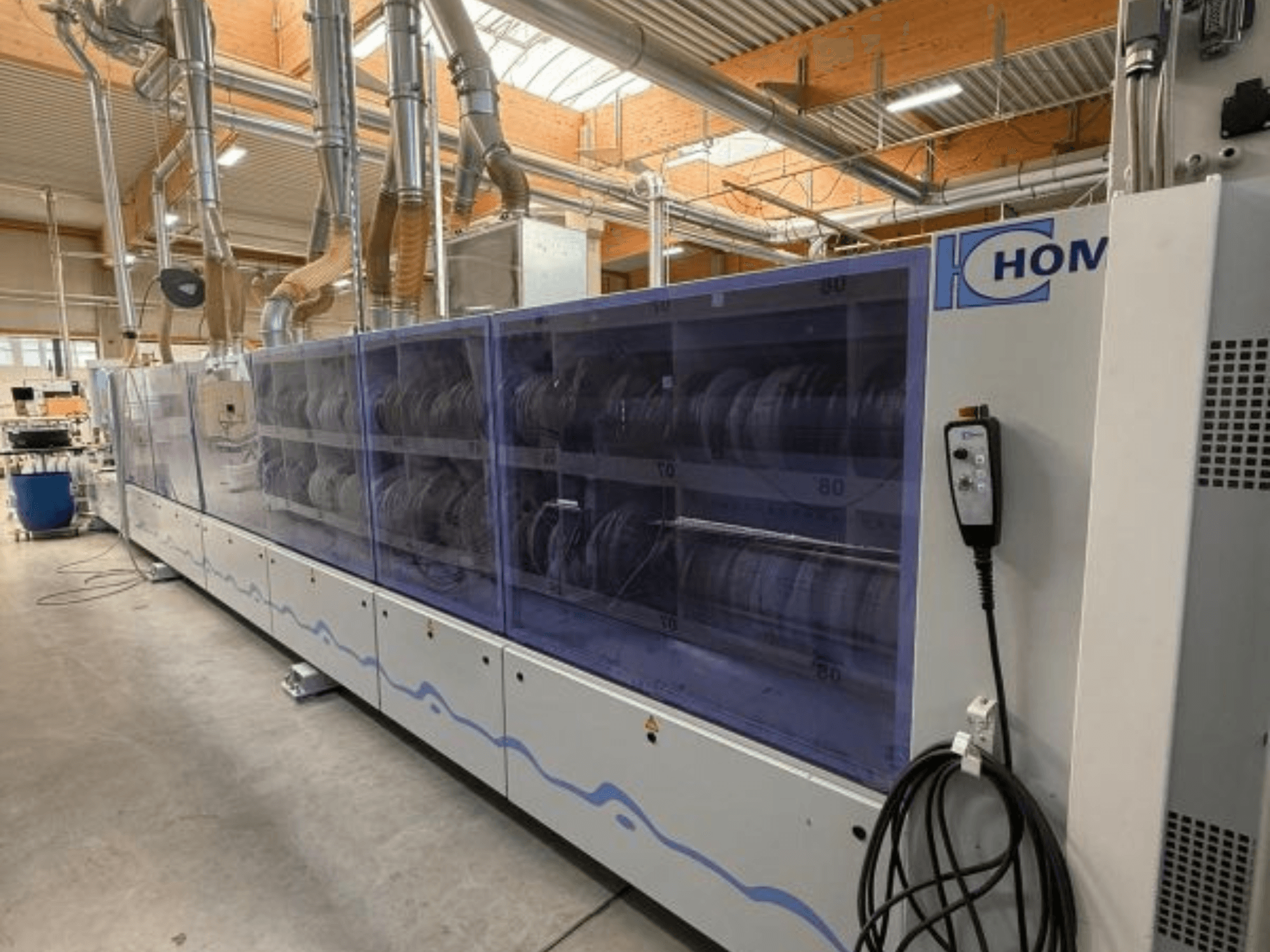 Lavadora industrial HOM, vista frontal, con panel transparente que muestra la vajilla; panel de control con botones en el lateral.