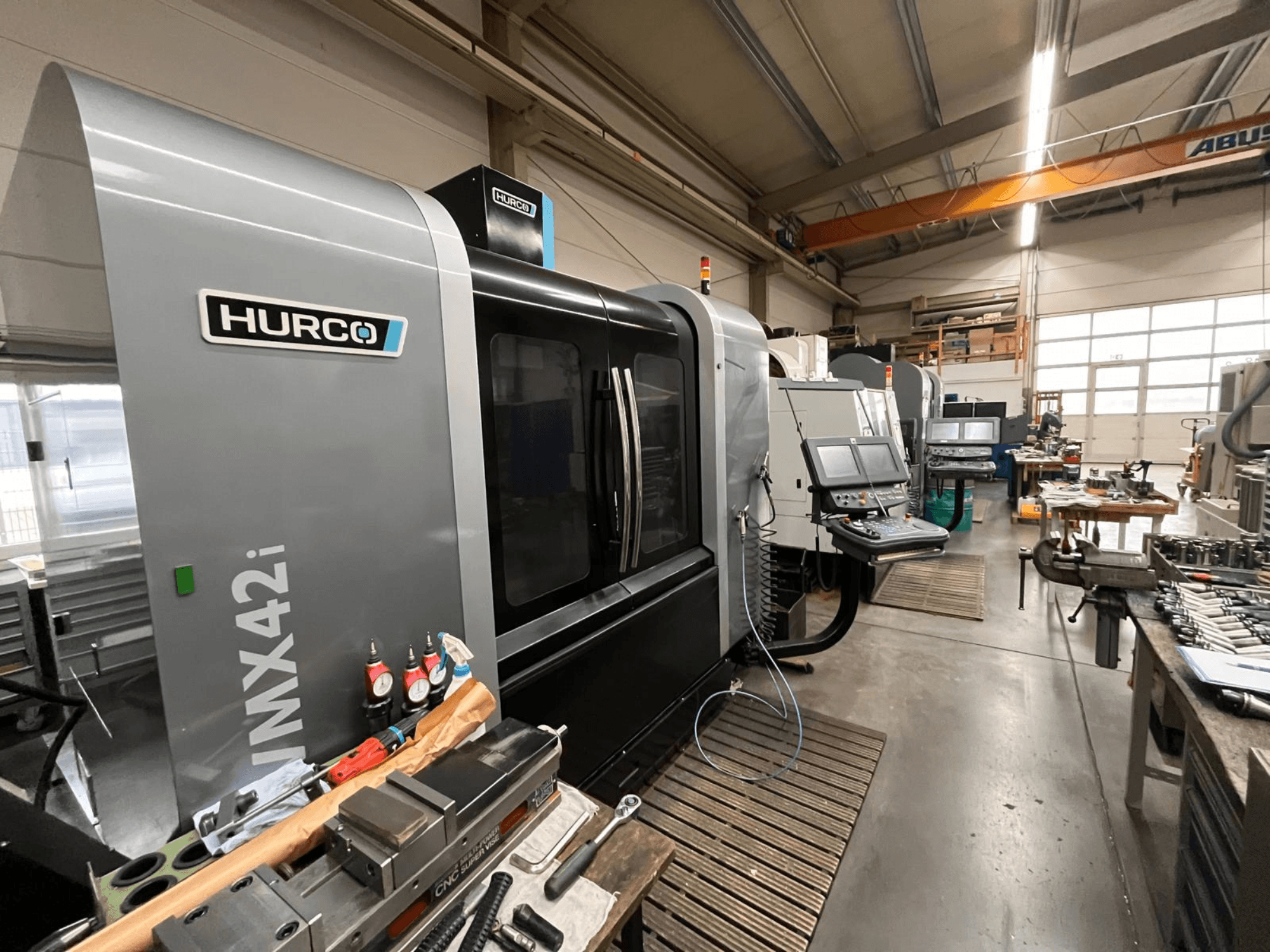 Máquina CNC Hurco VMX42i en un taller, vista frontal. Presenta panel de control, carrocería gris y entorno industrial.