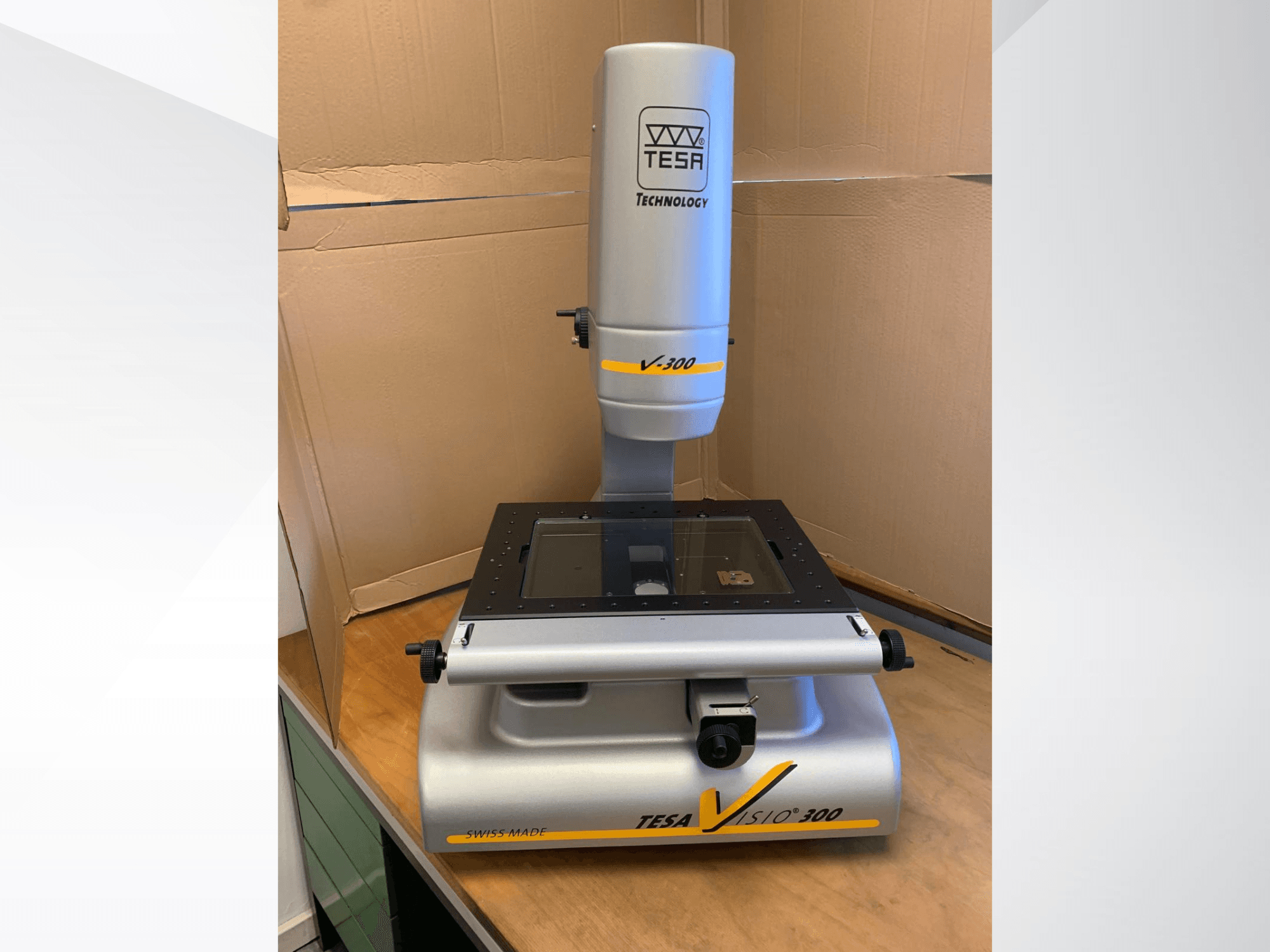 Máquina de medición óptica TESA Visio 300, vista frontal, presenta una superficie de medición clara y componentes ajustables. Fabricada en Suiza.