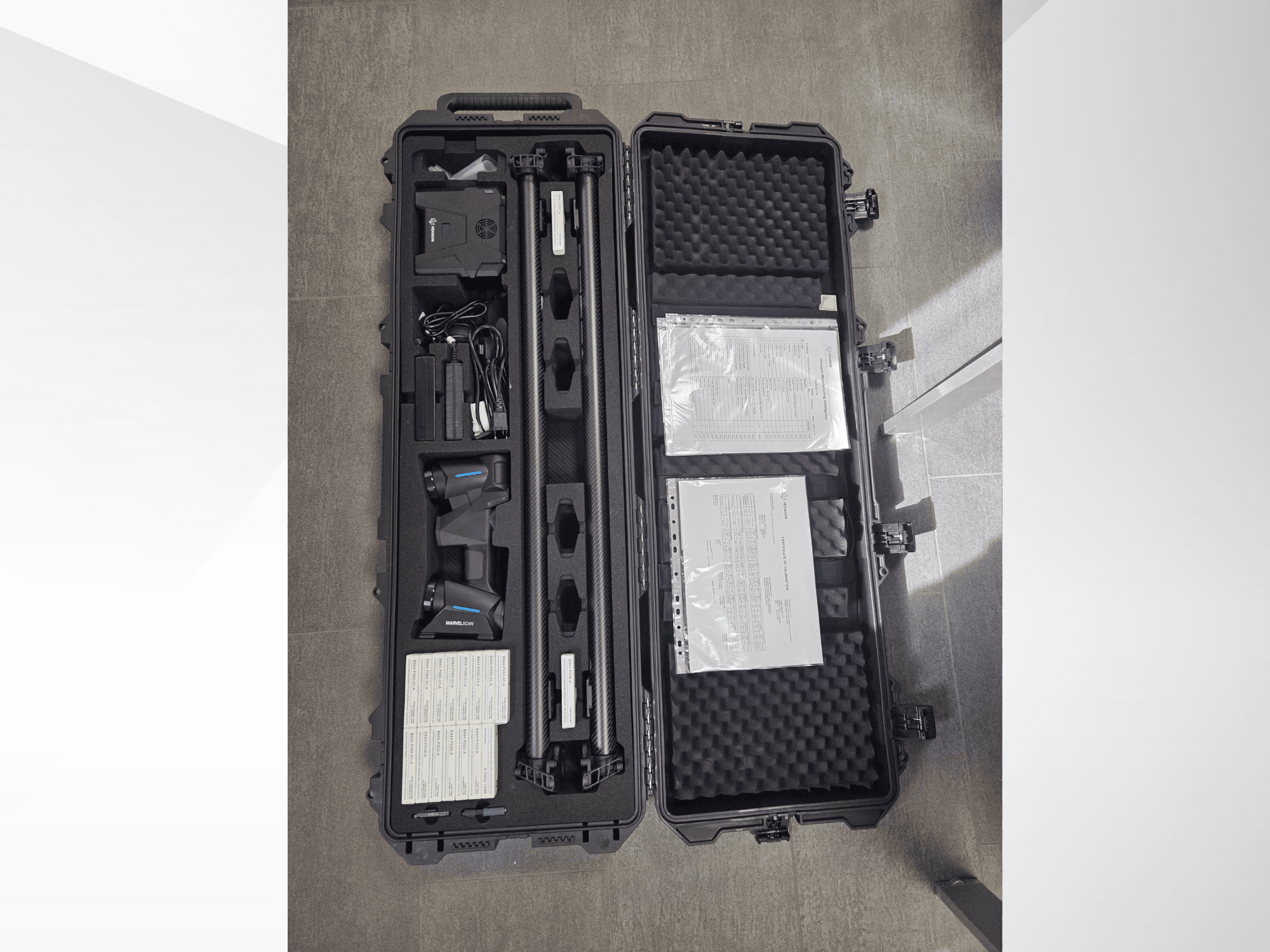 Equipo CMM Hexagon MARVEL en un maletín negro, que incluye varios sensores, cables y documentación; vista desde arriba.
