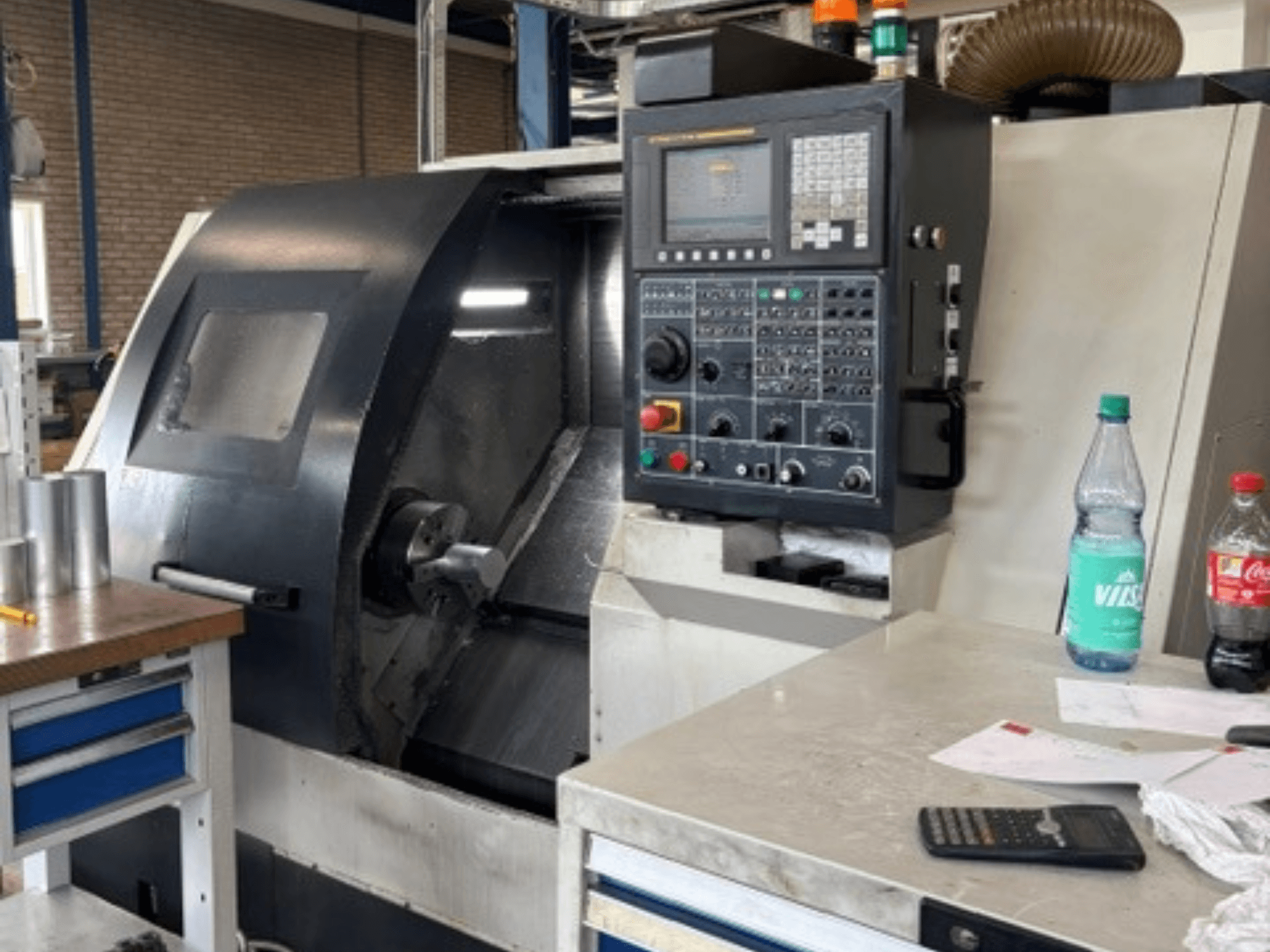 Torno horizontal Leadwell T-7, vista frontal, con el panel de control, la pieza de trabajo sobre el soporte de herramientas y detalles del espacio de trabajo a la vista.