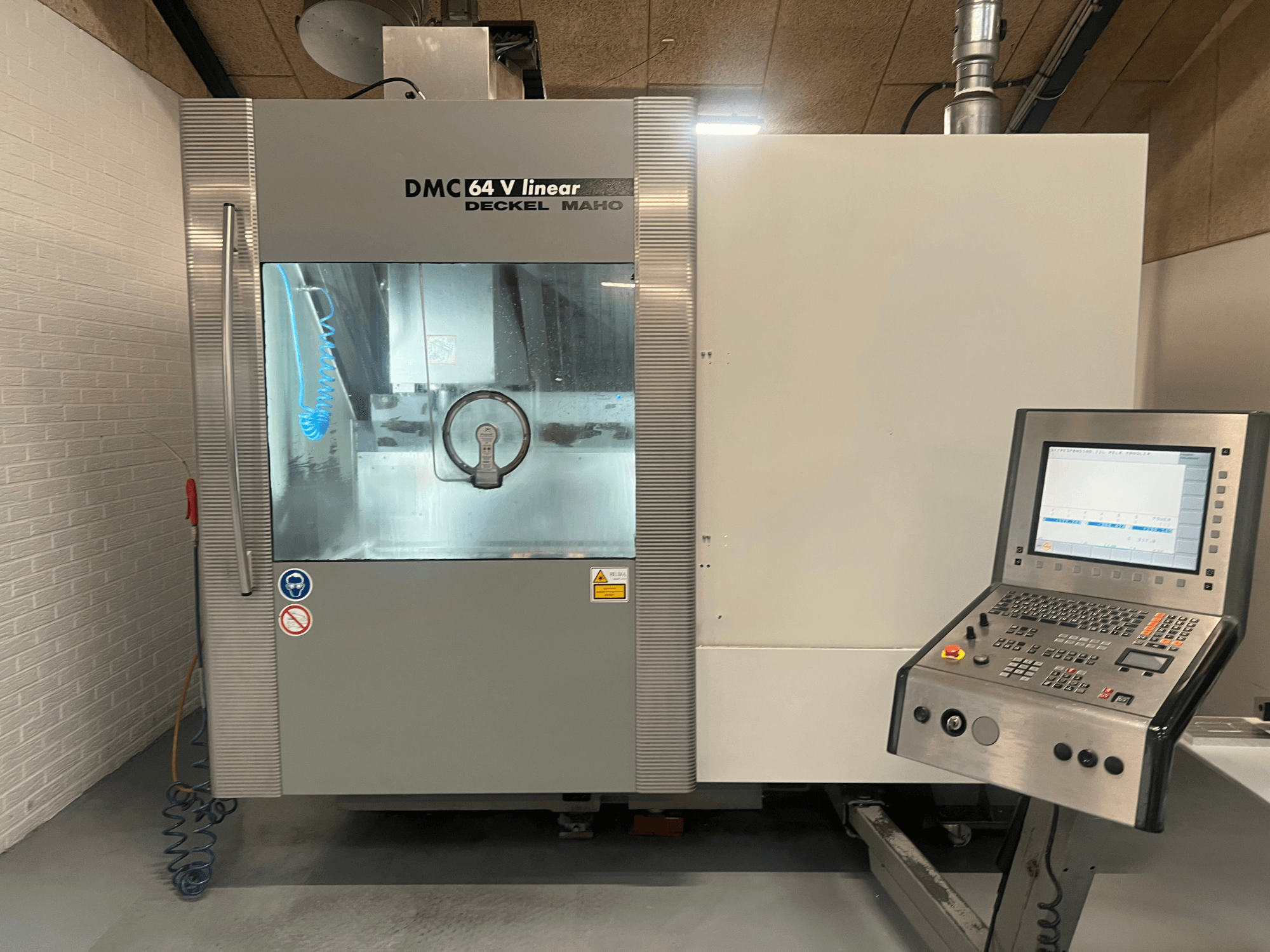 DMC 64 V Linear de Deckel Maho, vista frontal del centro de mecanizado CNC con el panel de control y la boquilla de refrigerante visibles.