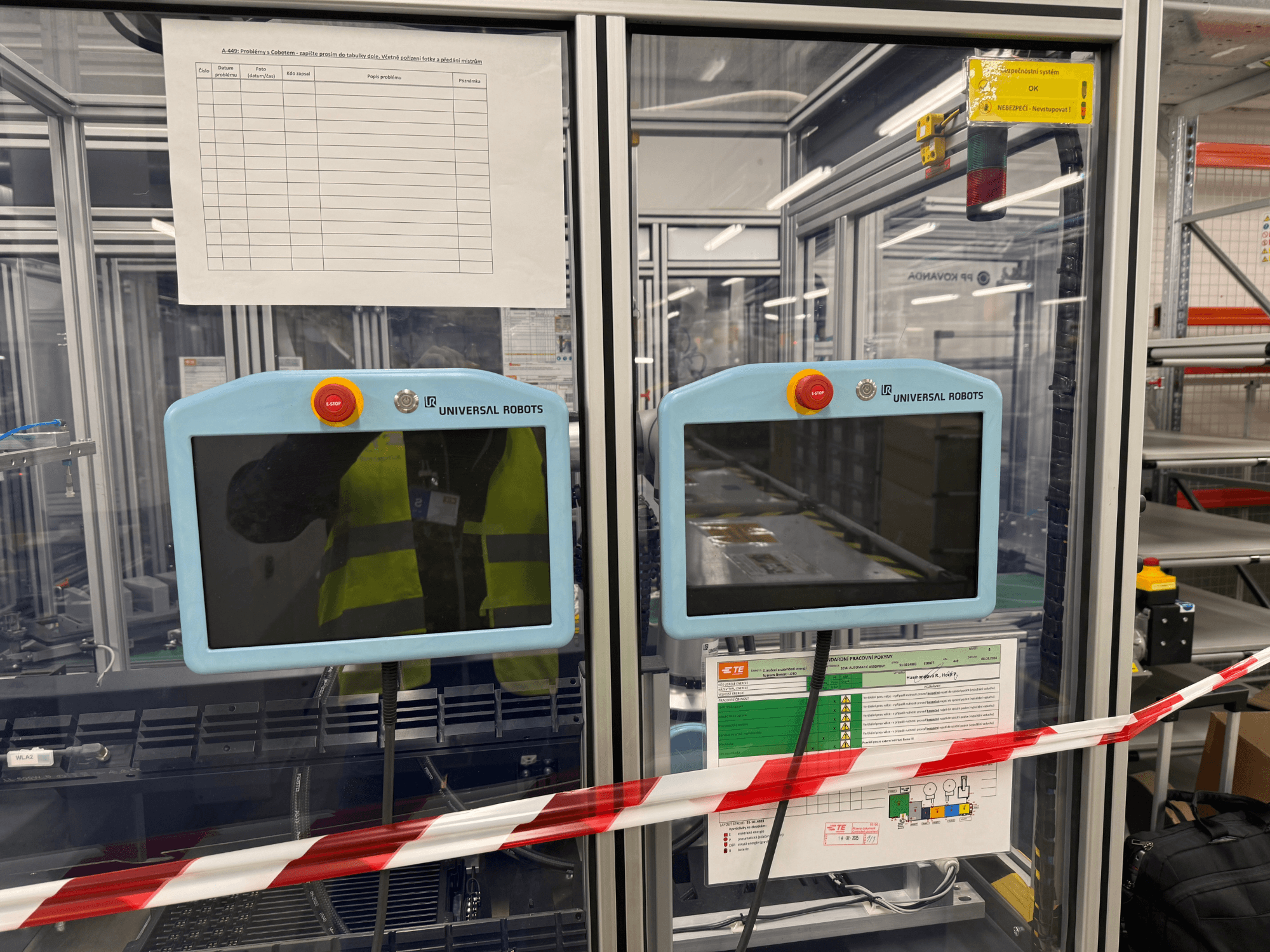 Panel de control para el brazo robótico UR5 e de Universal Robots, con dos monitores, botones de parada de emergencia e instrucciones de seguridad.