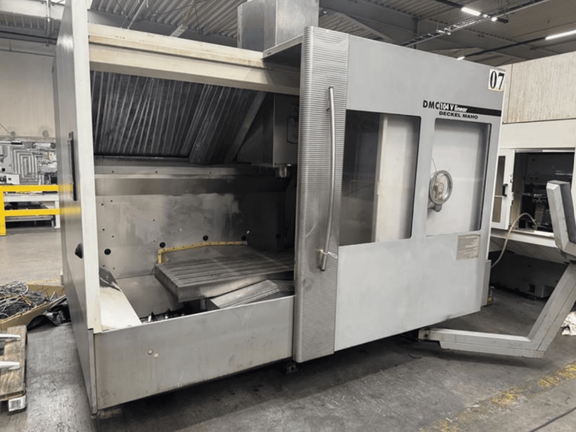 Máquina lineal DMC 104 V de Deckel Maho, vista frontal, con una zona de mecanizado vacía con una gran mesa de trabajo.