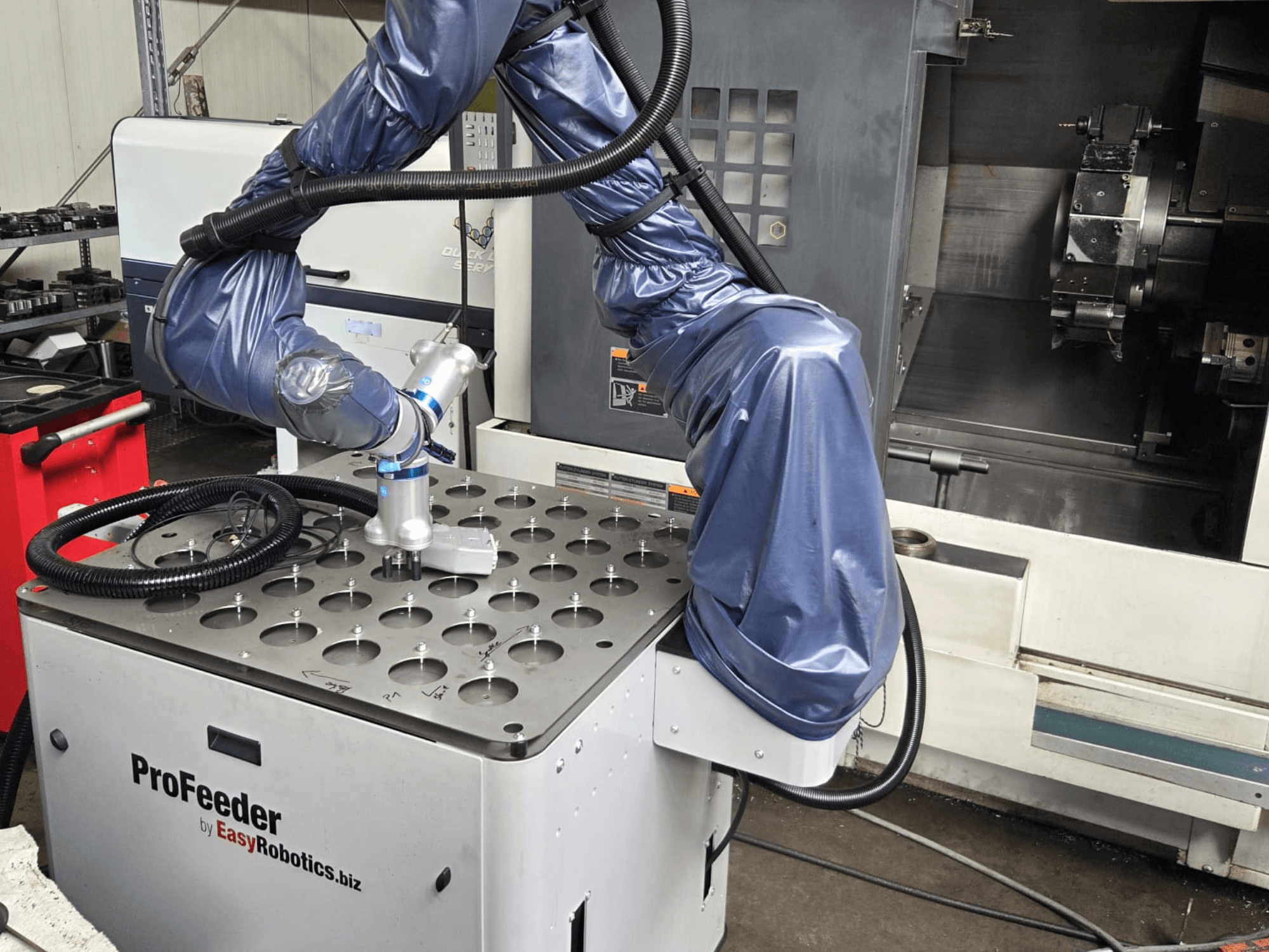 Robot colaborativo EASYROBOTICS ProFeeder desde una vista frontal, con un brazo robótico colocado sobre una mesa metálica perforada.