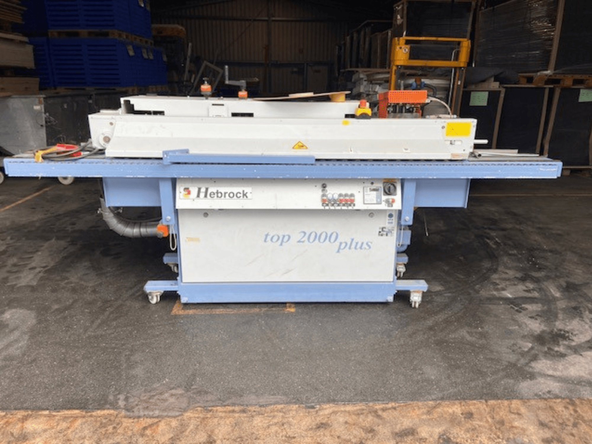 Hebrock Top 2000 Plus, vista frontal; máquina eléctrica industrial con panel de control, ruedas para movilidad y etiquetas de seguridad visibles.