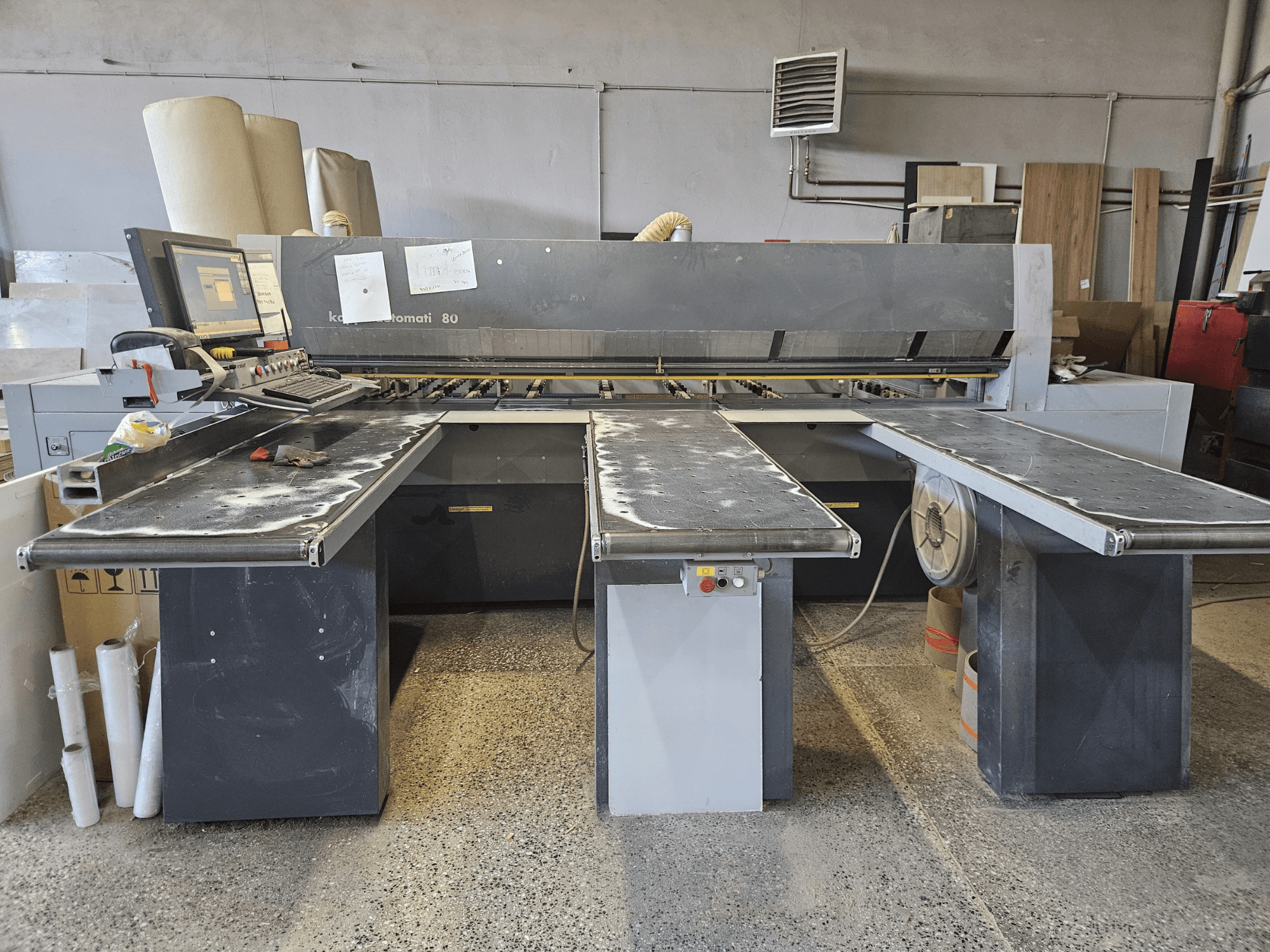 Máquina KAPPA Automati 80, vista frontal, con tres mesas planas, panel de control y serrín esparcido por las superficies.
