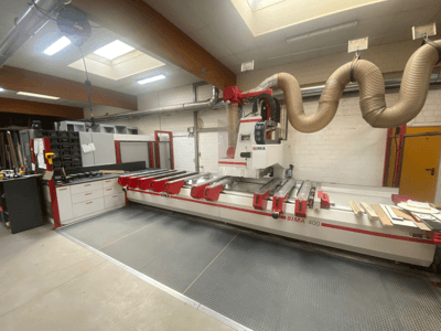 Máquina CNC BIMA 400 vista de frente, con un diseño en rojo y blanco, y un sistema de extracción de polvo.