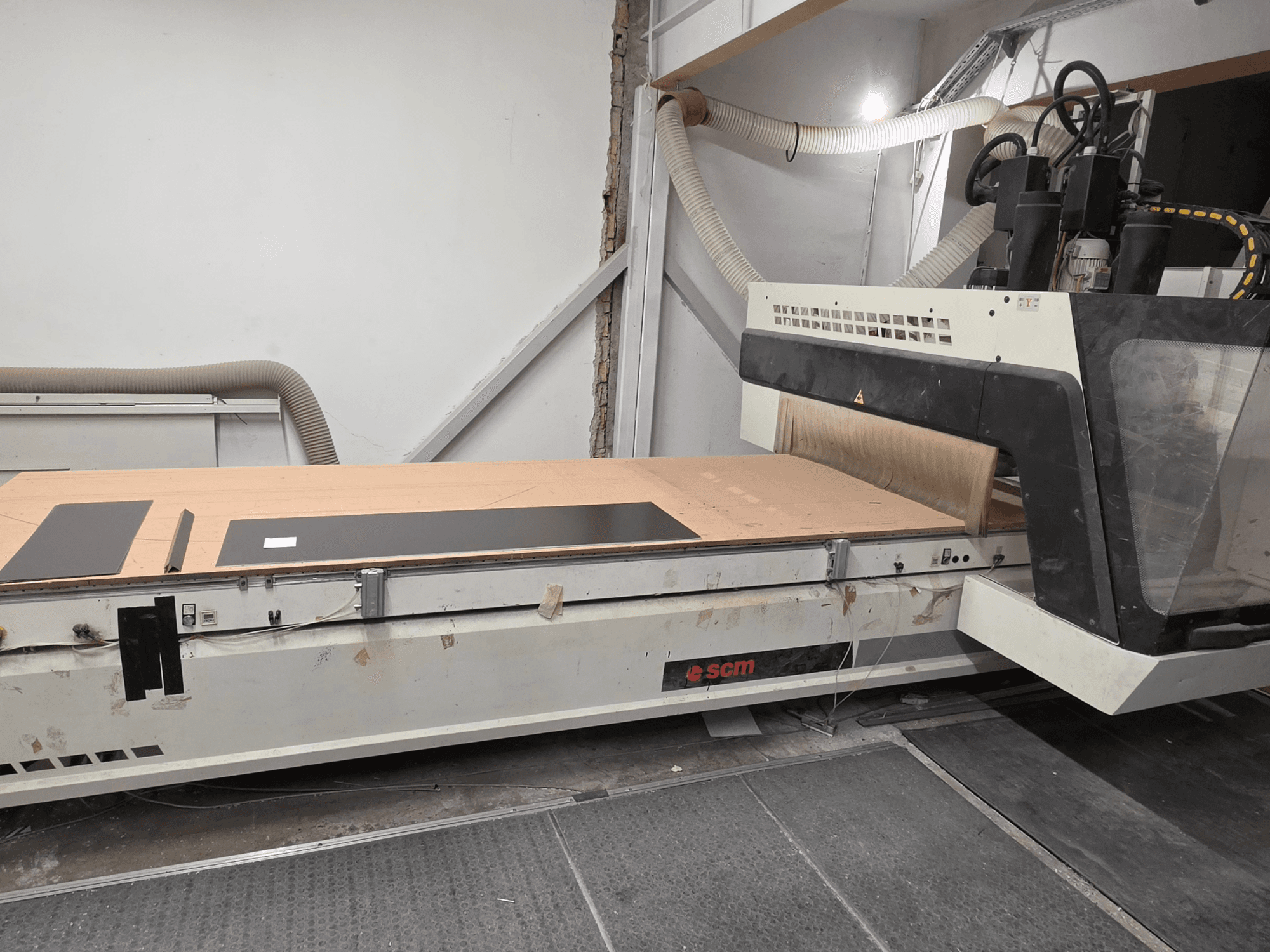 Centro de mecanizado de madera CNC SCM RECORD 132 en vista lateral, con una mesa de trabajo plana, piezas de trabajo negras y un sistema de recogida de polvo.