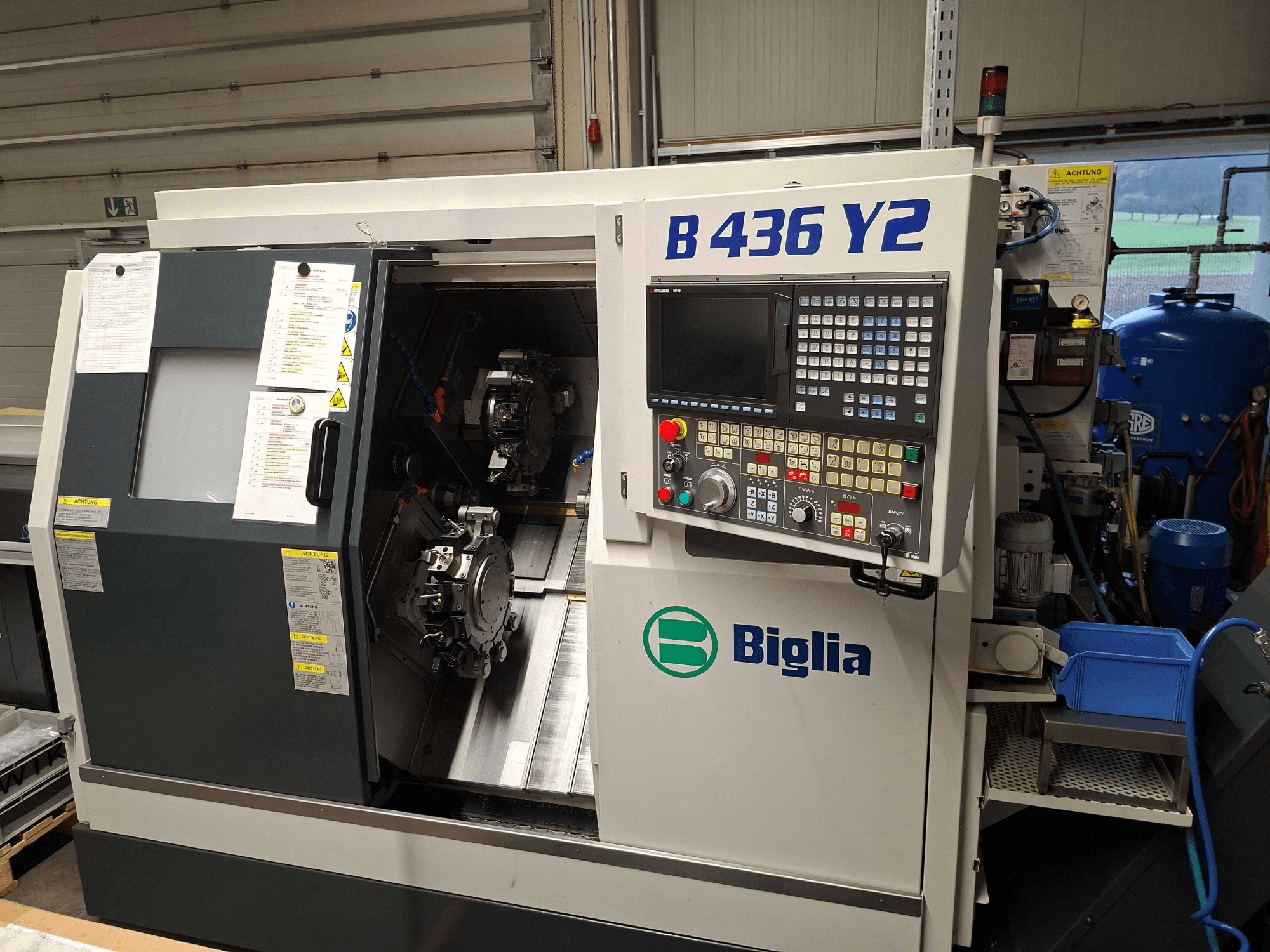 Torno CNC Biglia B 436 Y2 en vista lateral, con husillos dobles y panel de control con botones y pantalla para operaciones.