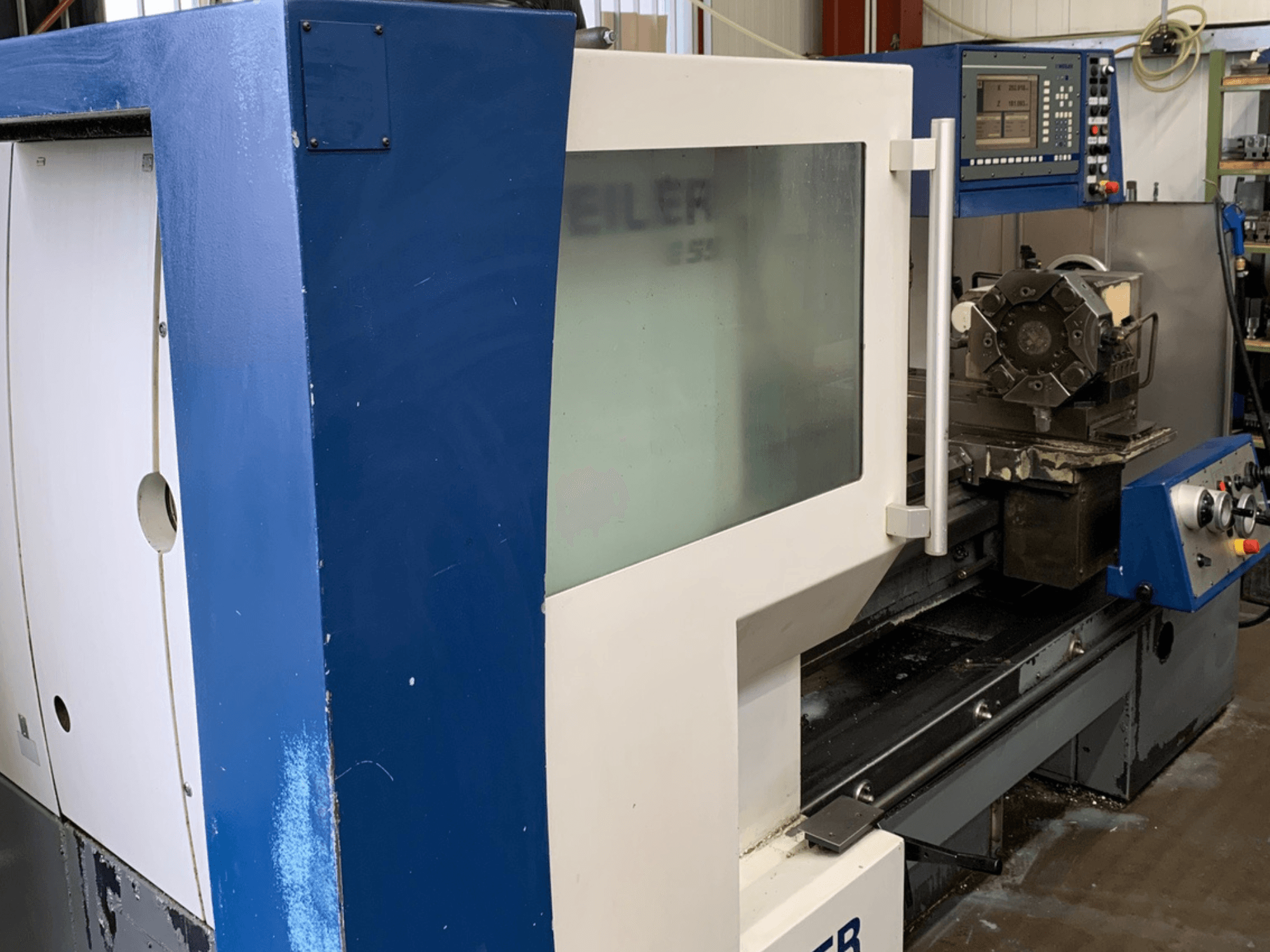 Máquina de torneado horizontal Weiler E55X1000, vista lateral que muestra el panel de control y la configuración de la herramienta de corte.