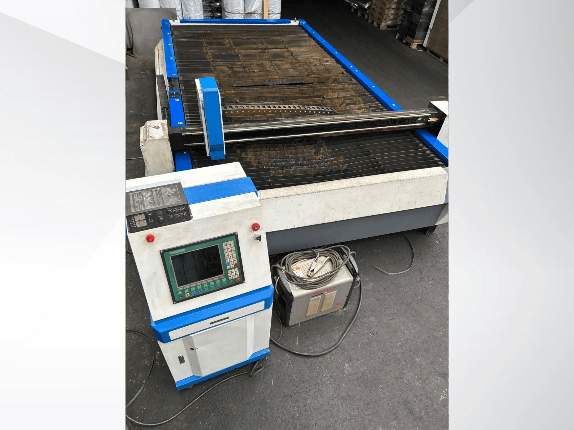 Máquina de corte por plasma CNC con panel de control, vista frontal, con acentos azules y cables en el suelo.