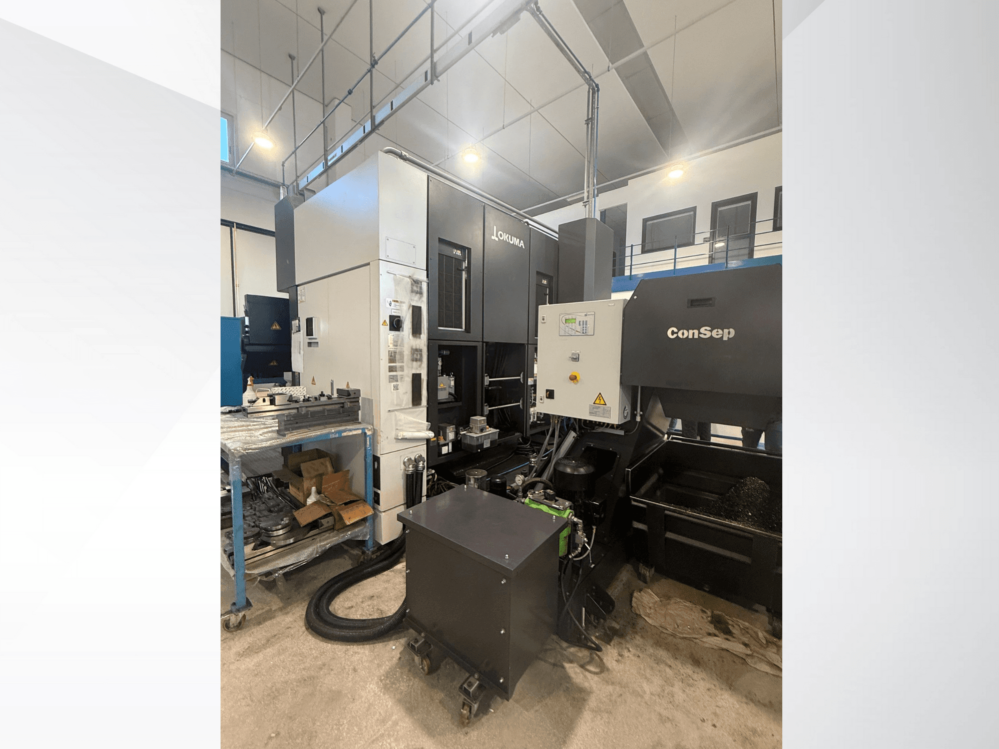 Centro de mecanizado Okuma con unidad ConSep, vista lateral, visualización de controles y configuración industrial, incluido depósito de virutas metálicas.