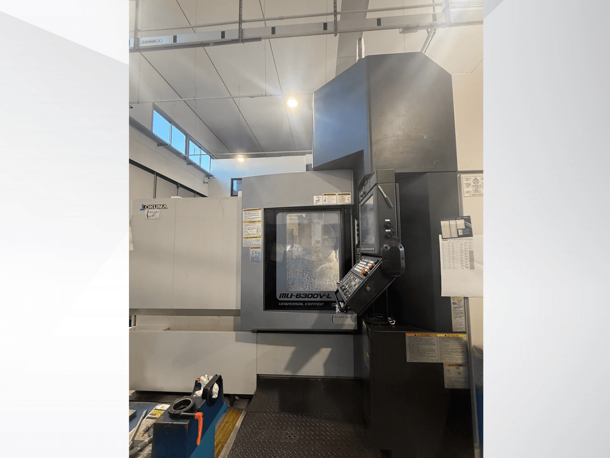Máquina CNC Okuma MU-6300V-L vista de frente, mostrando el panel de control y las etiquetas de seguridad.