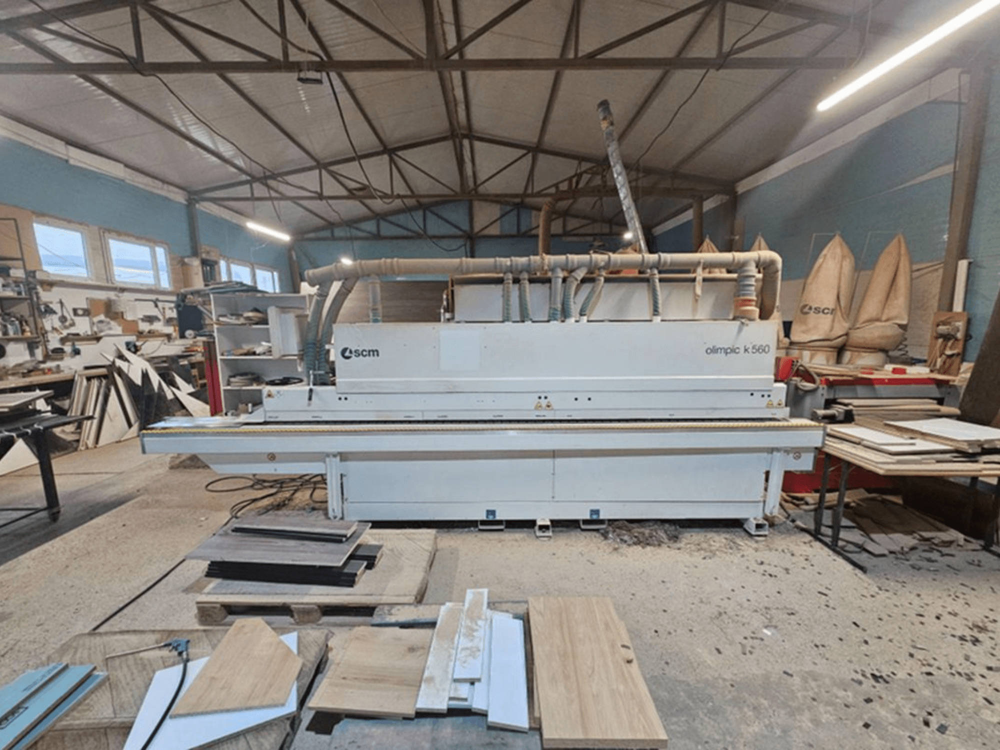 Máquina encintadora SCM Olimpic K 560 en un taller, vista frontal; entre sus características visibles destacan los rodillos de alimentación y el sistema de extracción.