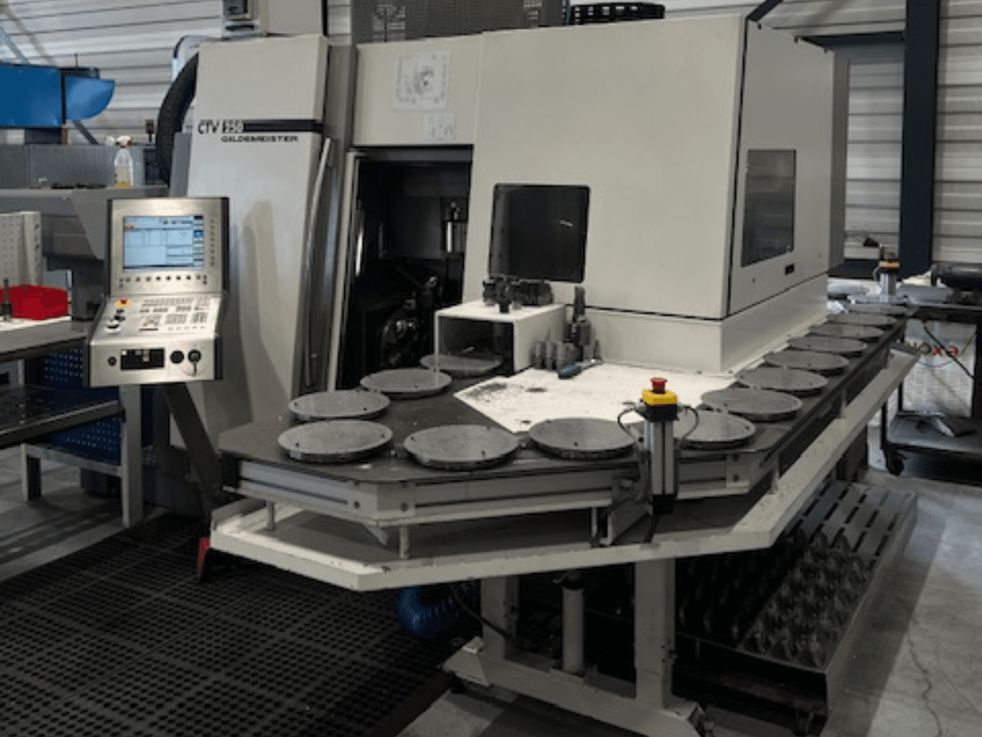 Texto alternativo: Unidad de mecanizado CTV E33 Goldmeister en un taller, vista frontal, con panel de control y múltiples plataformas de trabajo circulares.