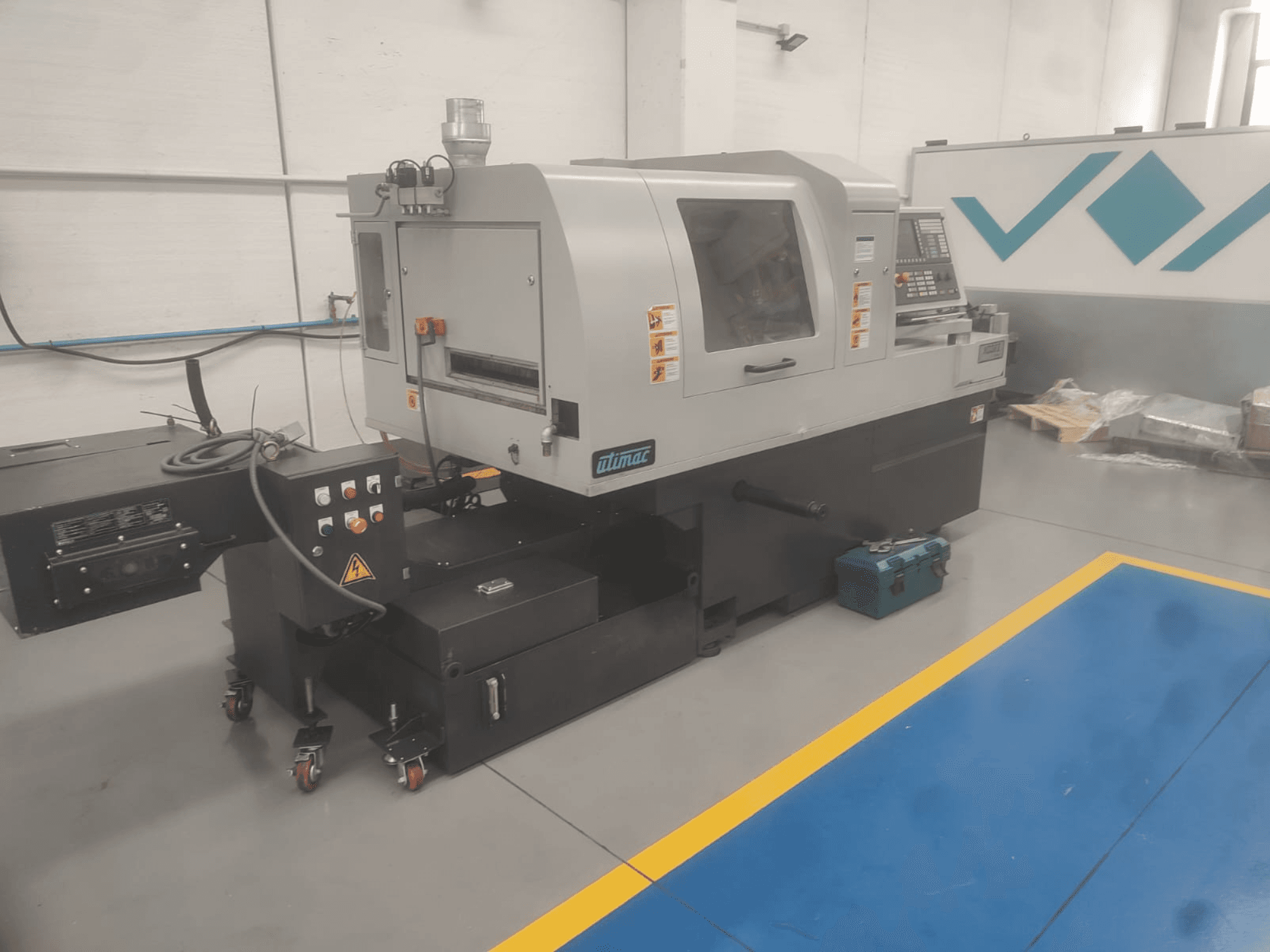 Torno de tipo suizo UTIMAC ISOLA XD 38 II, vista frontal, con panel de control y base con ruedas para movilidad.