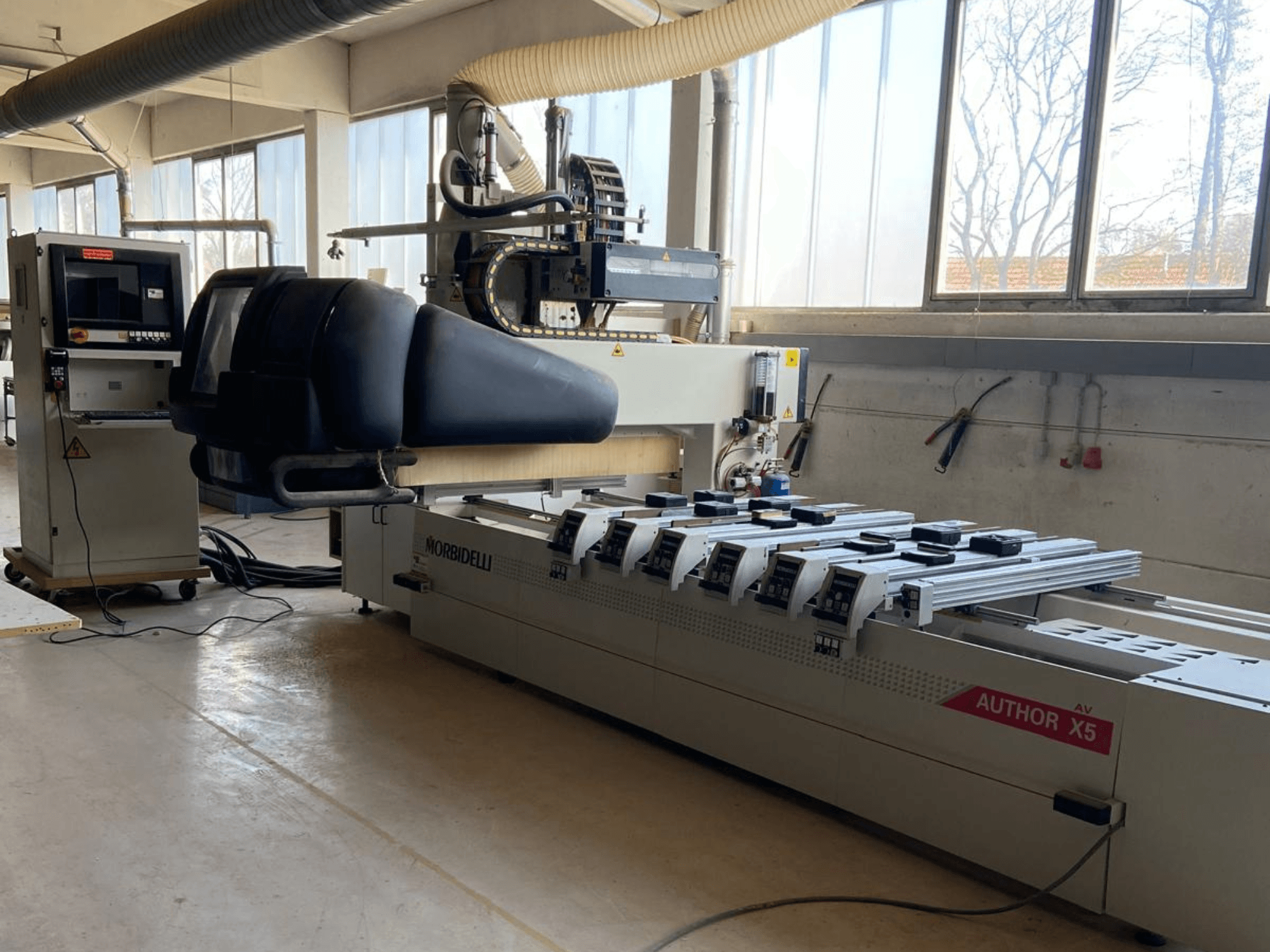 Centro de mecanizado CNC de madera MORBIDELLI Author X5 en un taller, mostrando el panel de control y la zona de mecanizado desde una vista lateral.