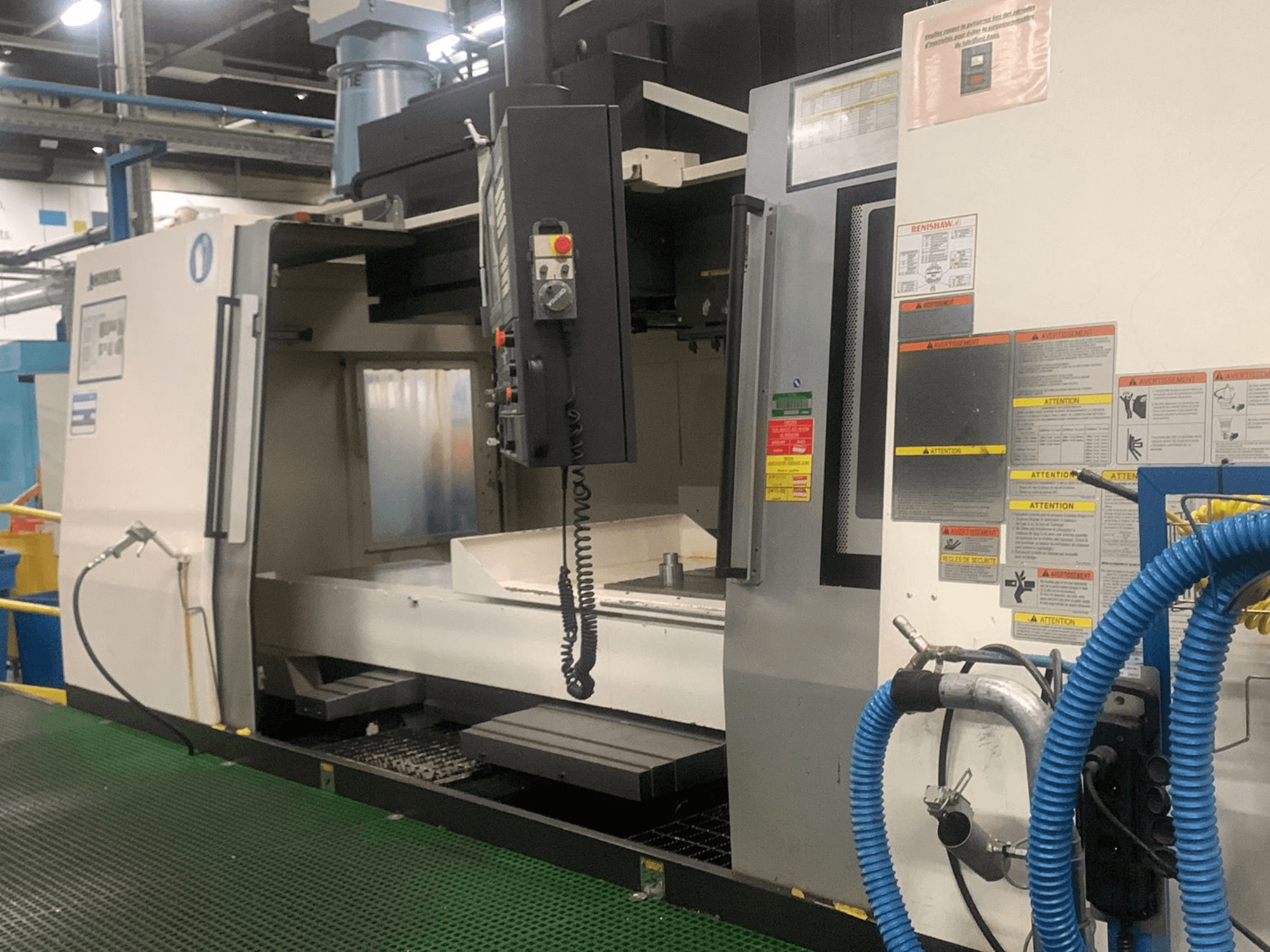 Centro de mecanizado vertical Okuma Millac 852 VII, vista frontal, en la que se aprecian el panel de control, la zona del husillo y las etiquetas de seguridad.