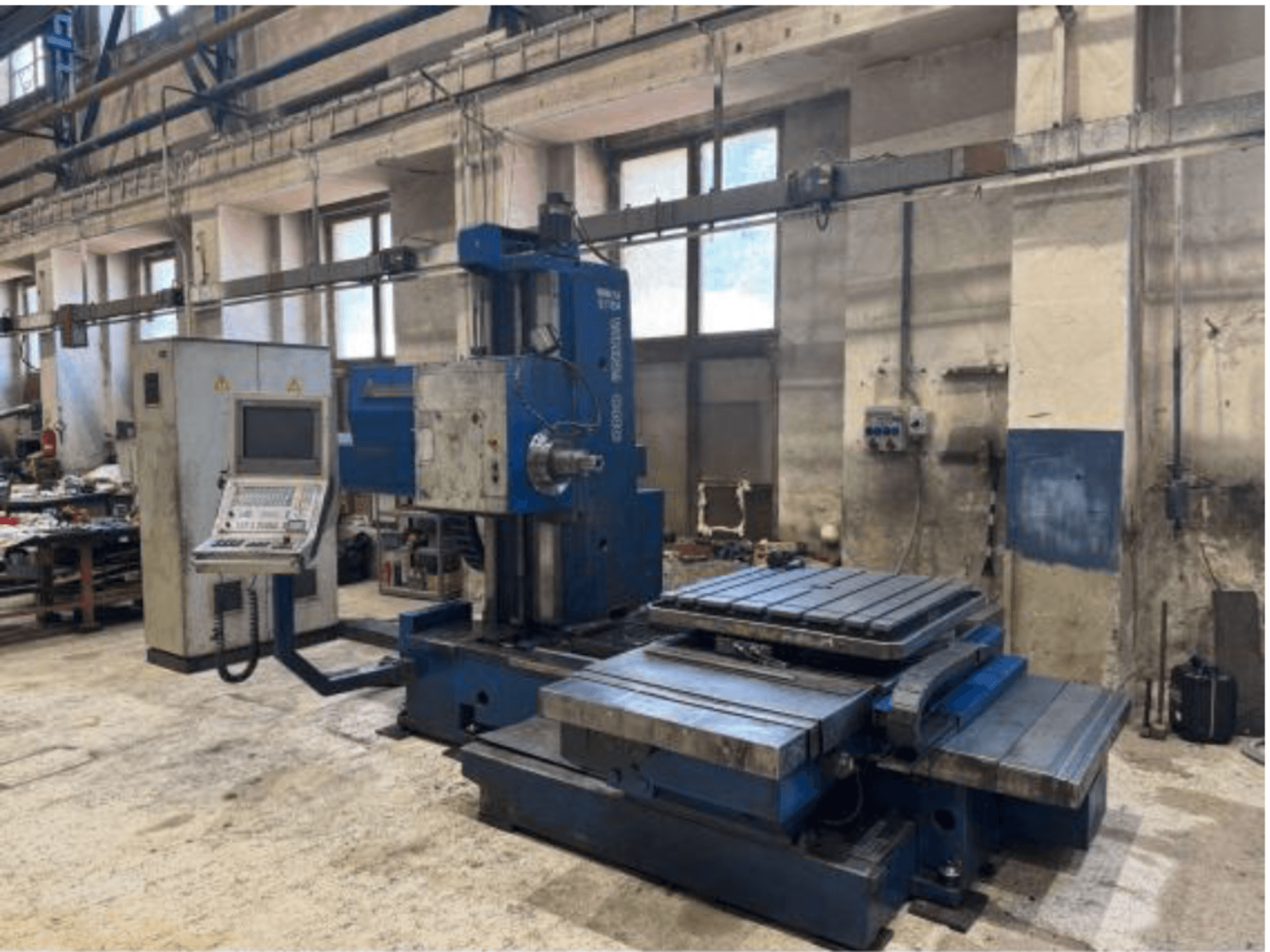 Máquina de mandrinado CNC TOS WHN 9 B vista de frente, con un panel de control y una amplia mesa de trabajo, instalada en un entorno de taller.