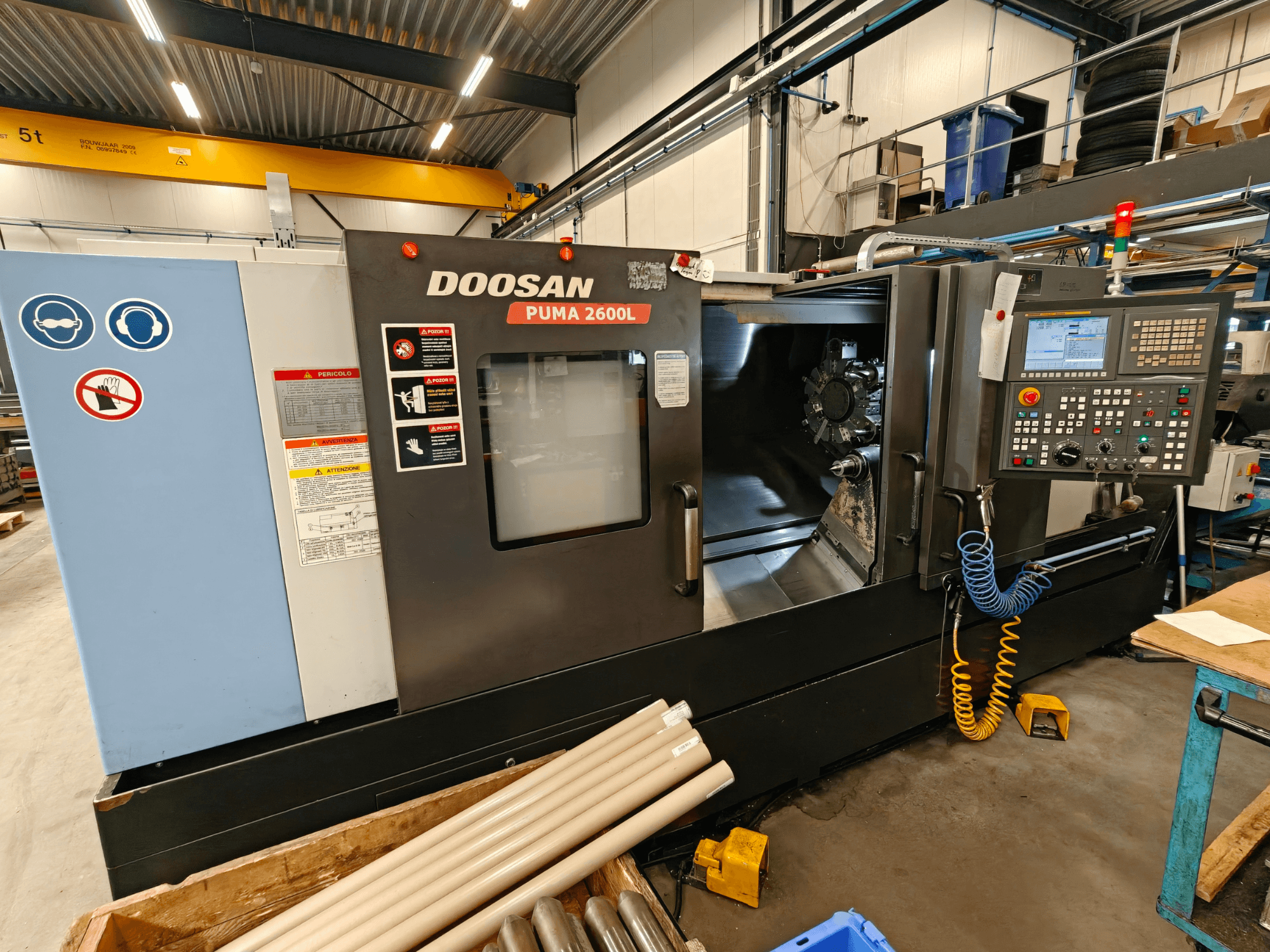 Tornos horizontales DOOSAN Puma 2600L en un taller, vista lateral mostrando el panel de control y la zona del husillo.