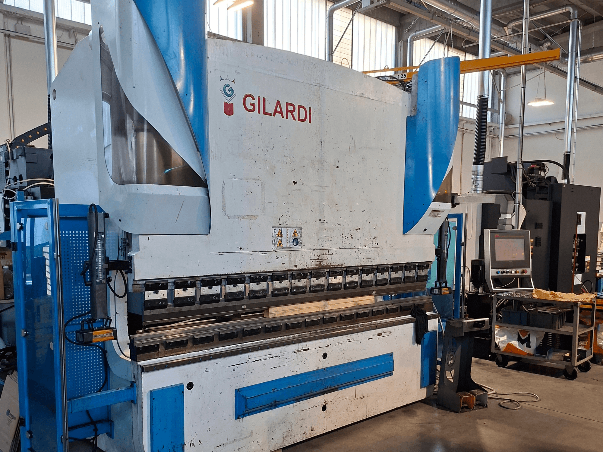 Prensa hidráulica GILARDI Italia 3,25, vista frontal, en la que se muestran los mandos de funcionamiento y detalles del entorno de producción.
