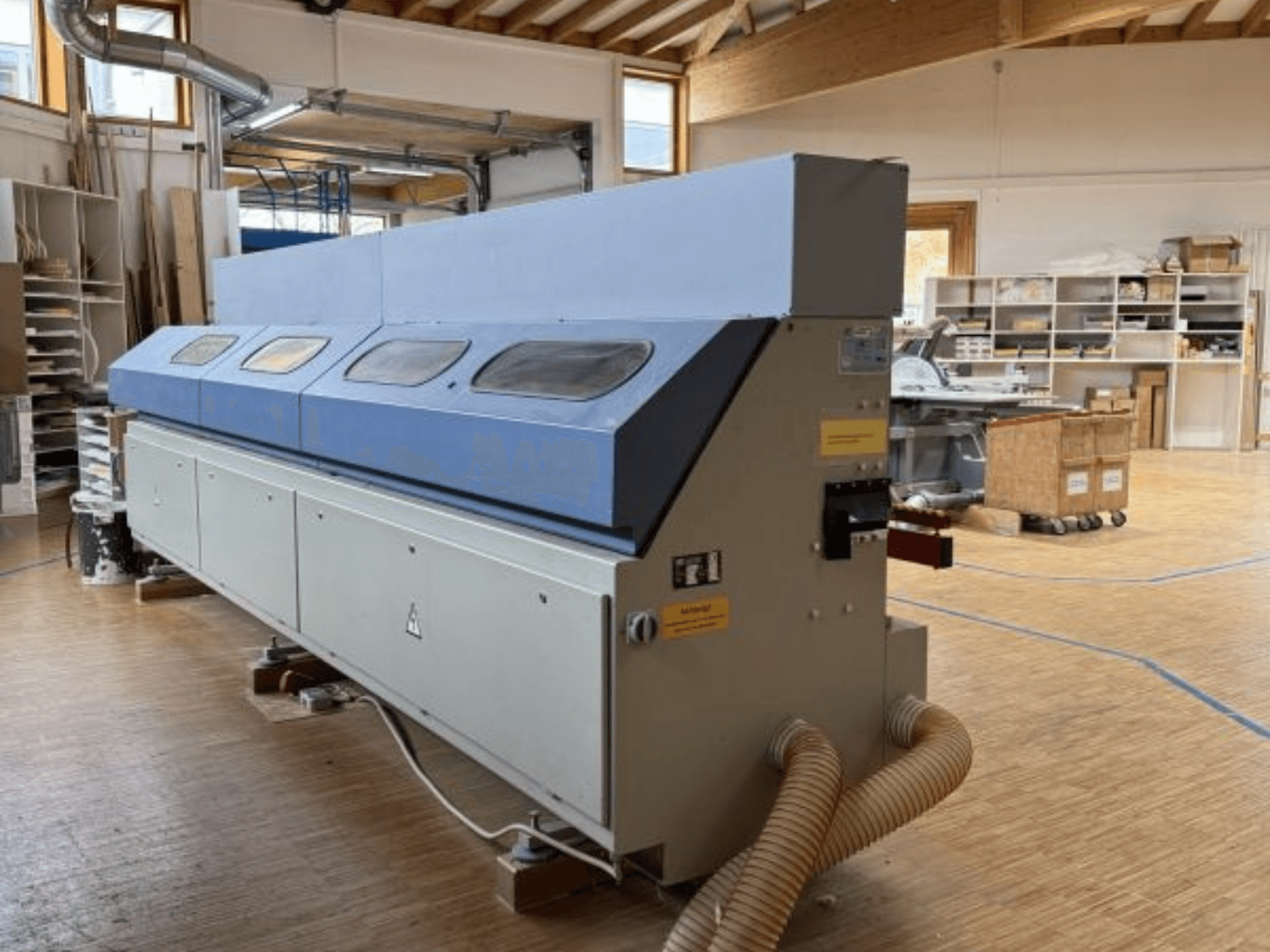 Chapadora de cantos OTT Pacific V6-F mostrada desde una vista lateral; presenta una larga parte superior azul y un panel de control con enganche para manguera.