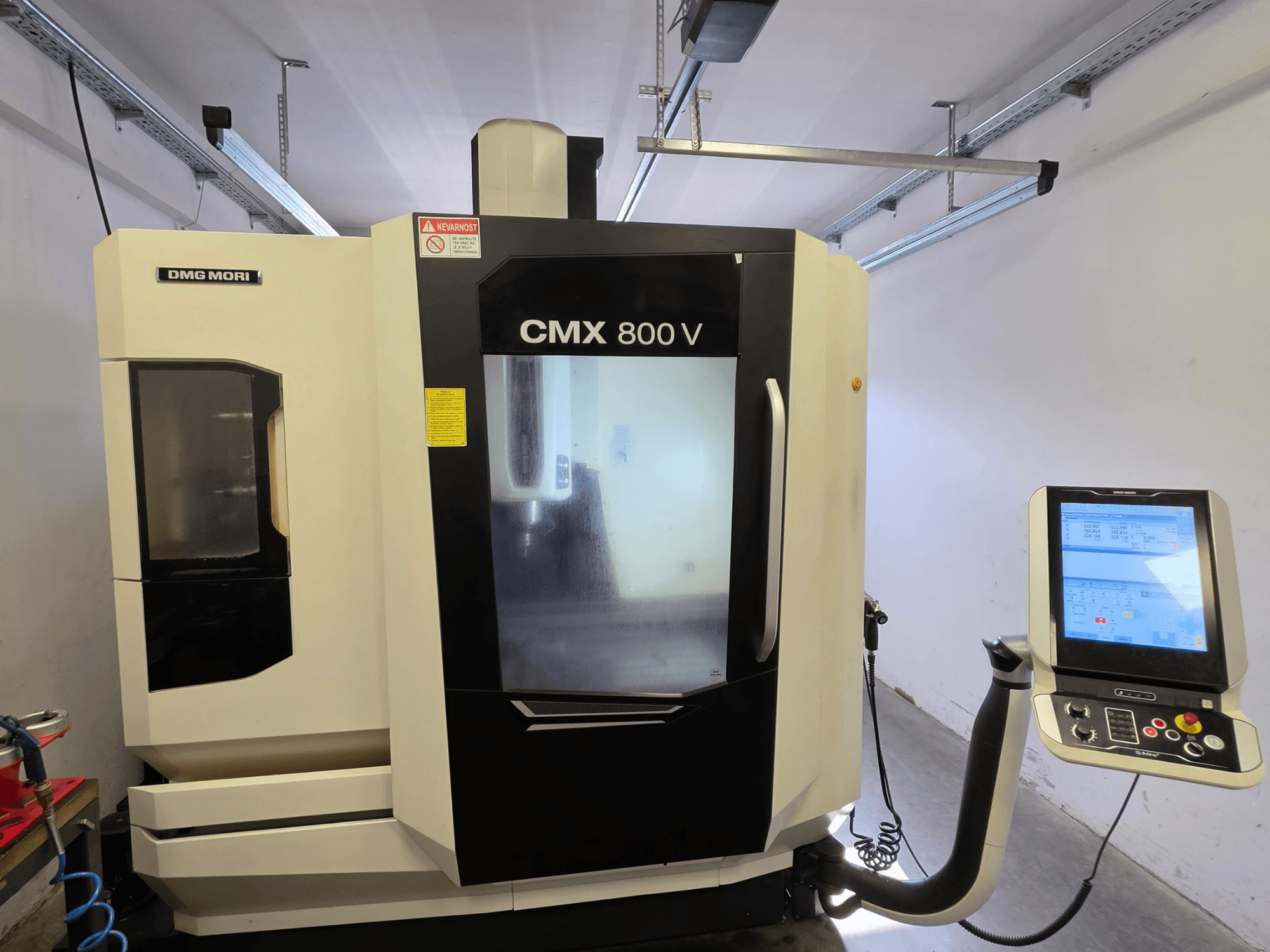 Centro de mecanizado vertical DMG MORI CMX 800V, vista frontal, con un panel de control con pantalla táctil y señalización de seguridad clara.