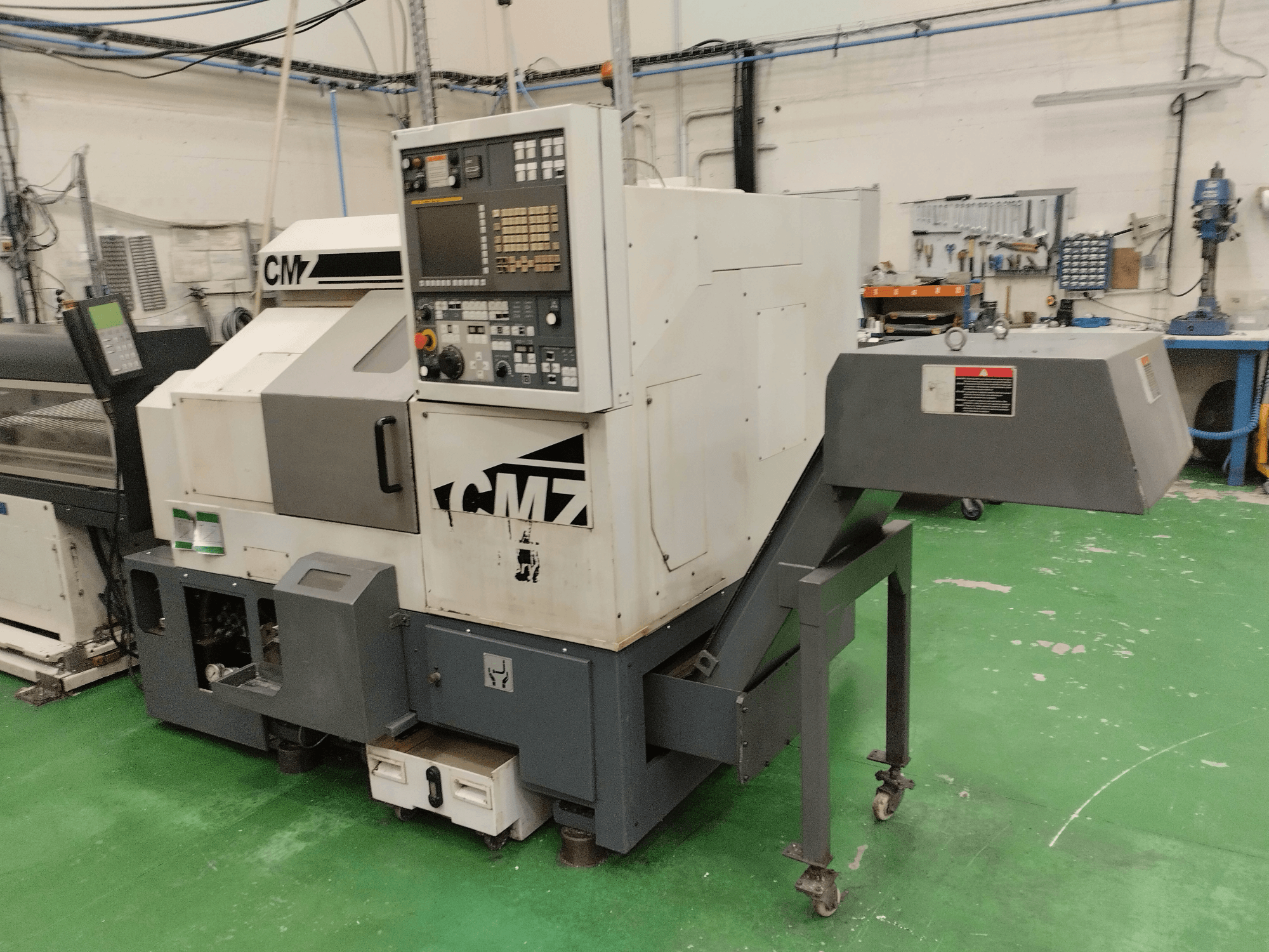 Centro de torneado y fresado CMZ TB-67M en vista frontal, con panel de control y mecanismo de alimentación, colocado en un entorno de taller.