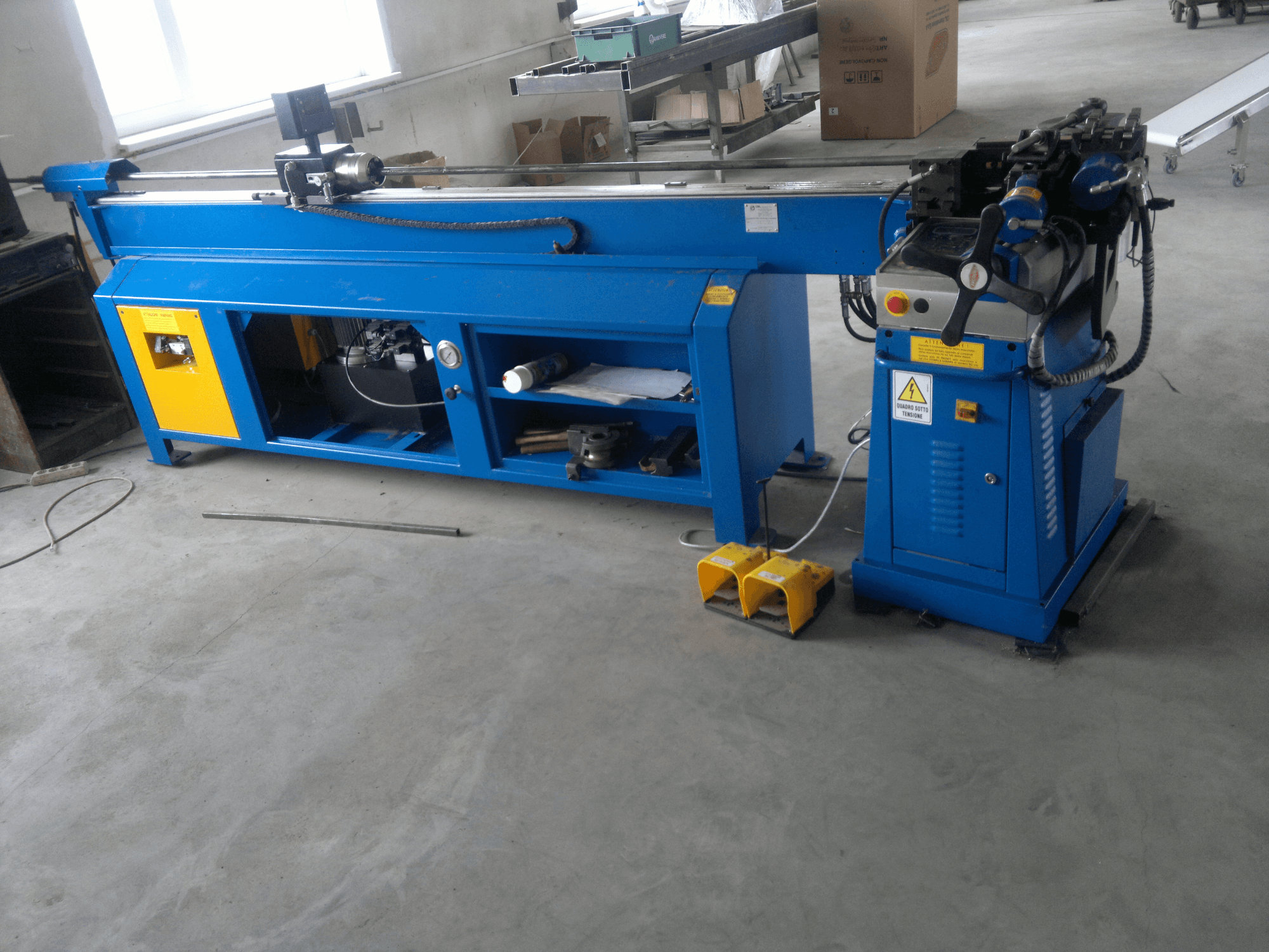 Máquina para trabajar la madera azul con detalles amarillos, vista lateral; dispone de panel de control, pedales y un conjunto de cuchillas giratorias.