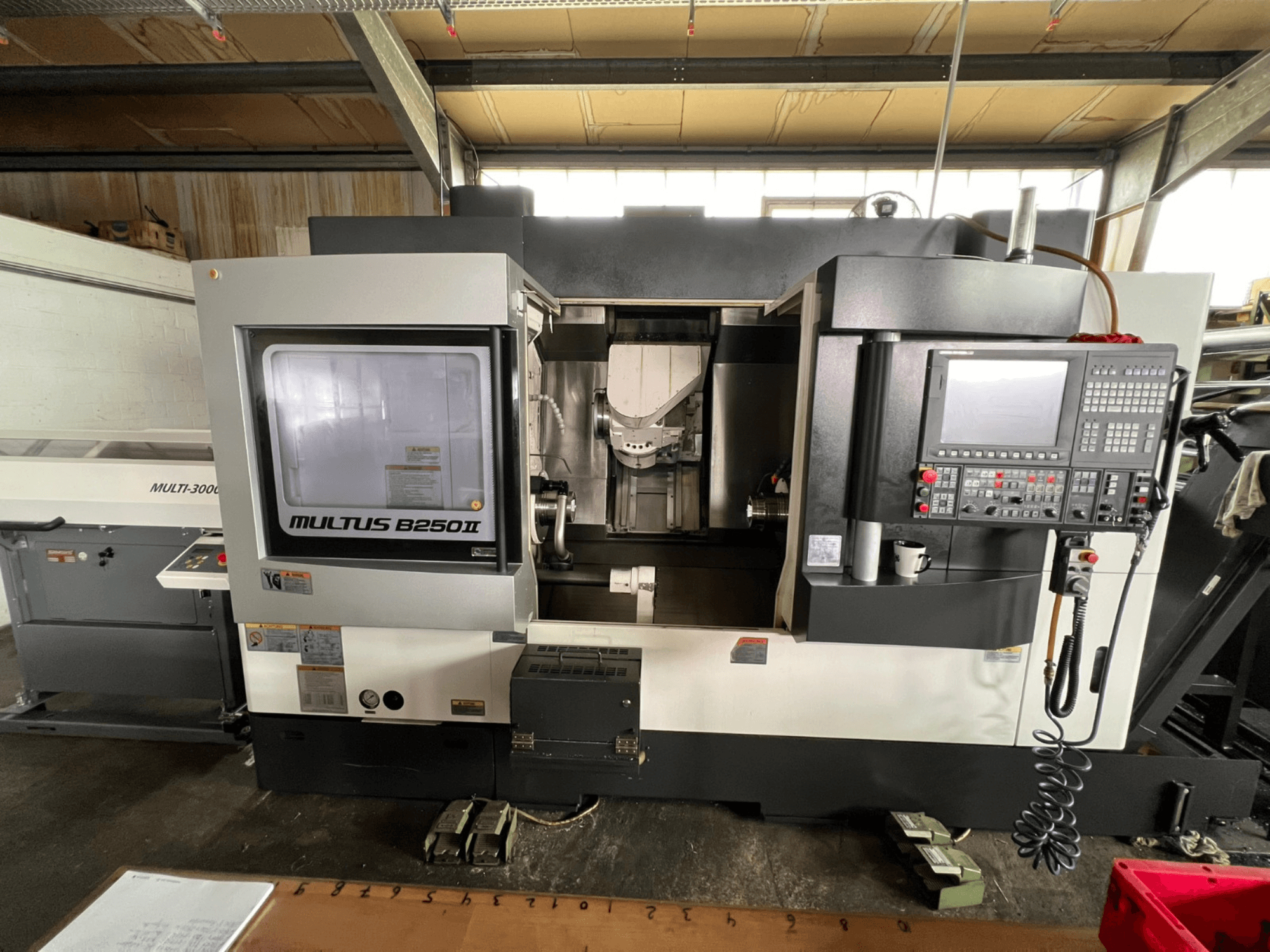 Centro de torneado y fresado Okuma Multus B250II MW, vista frontal, en la que se aprecian detalles del panel de control y de la zona de mecanizado.