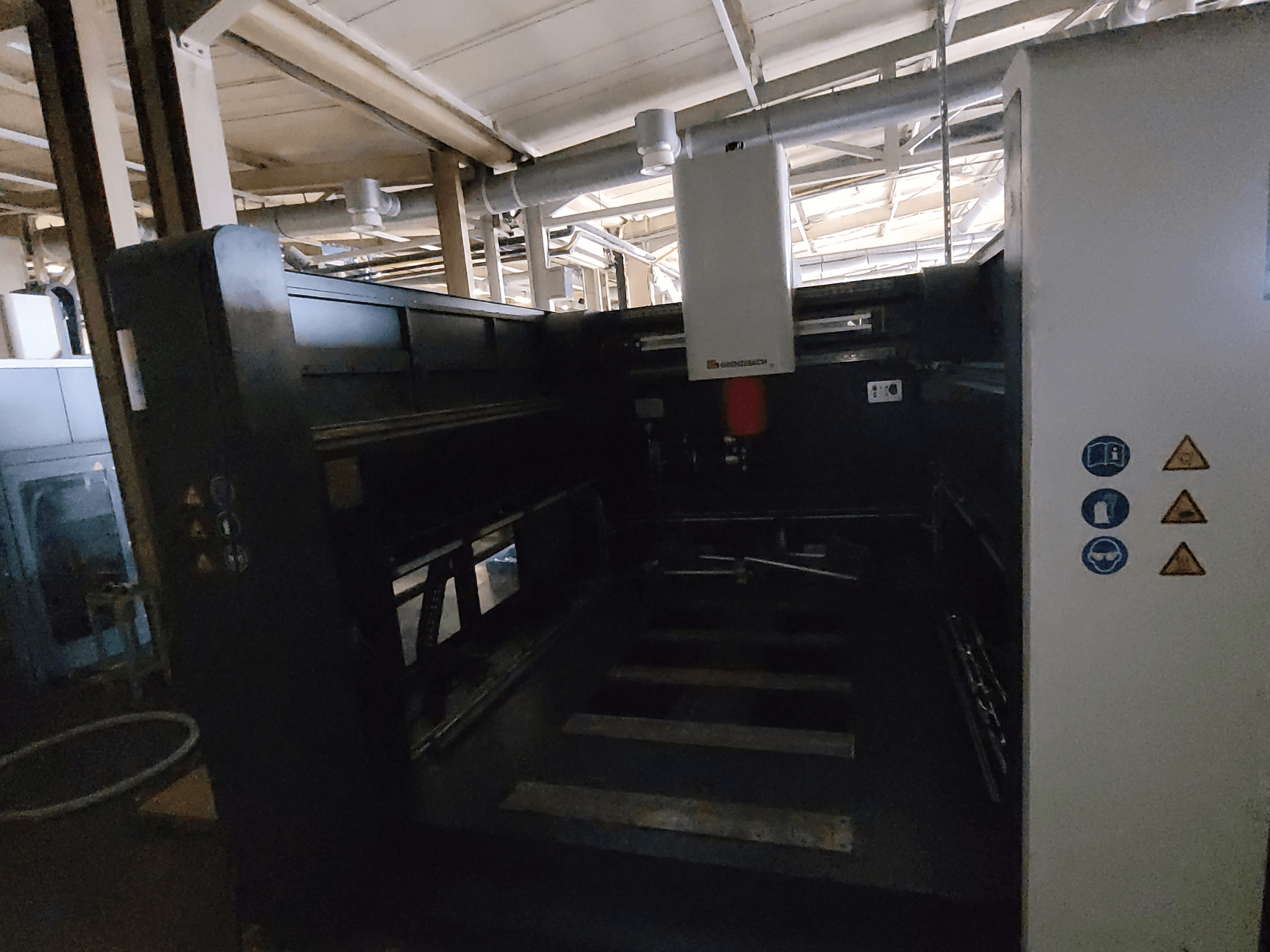 Máquina FSW DSM 3000 de GRENZEBACH, vista lateral en la que se aprecian los mandos, los símbolos de seguridad y el área de trabajo para las tareas de mecanizado.