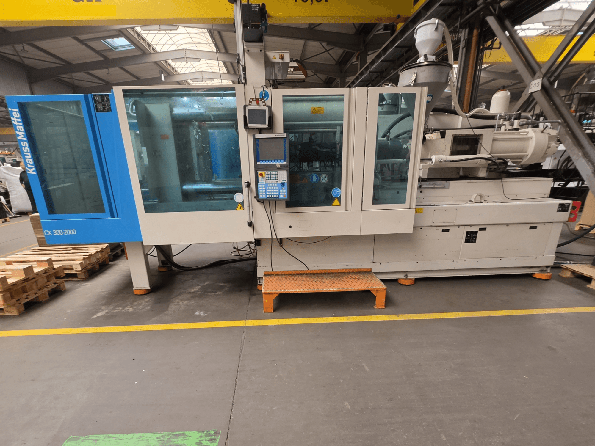 Máquina de moldeo por inyección hidráulica Krauss Maffei 300-2000 CX, vista lateral mostrando el panel de control y las grandes ventanas.