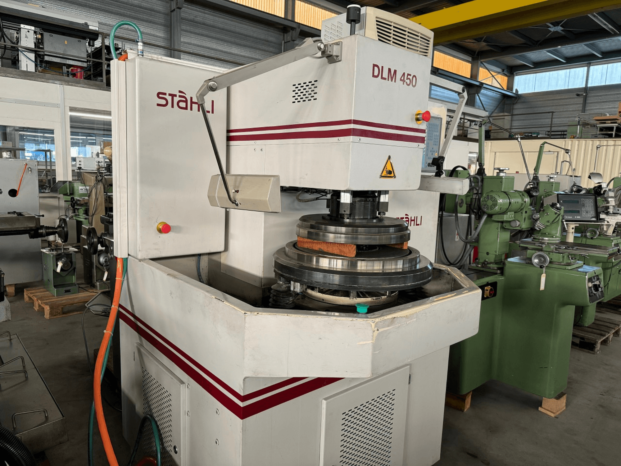 Rectificadora plana STAEHLI DLM 450, vista frontal con muela y panel de control, en un entorno industrial.