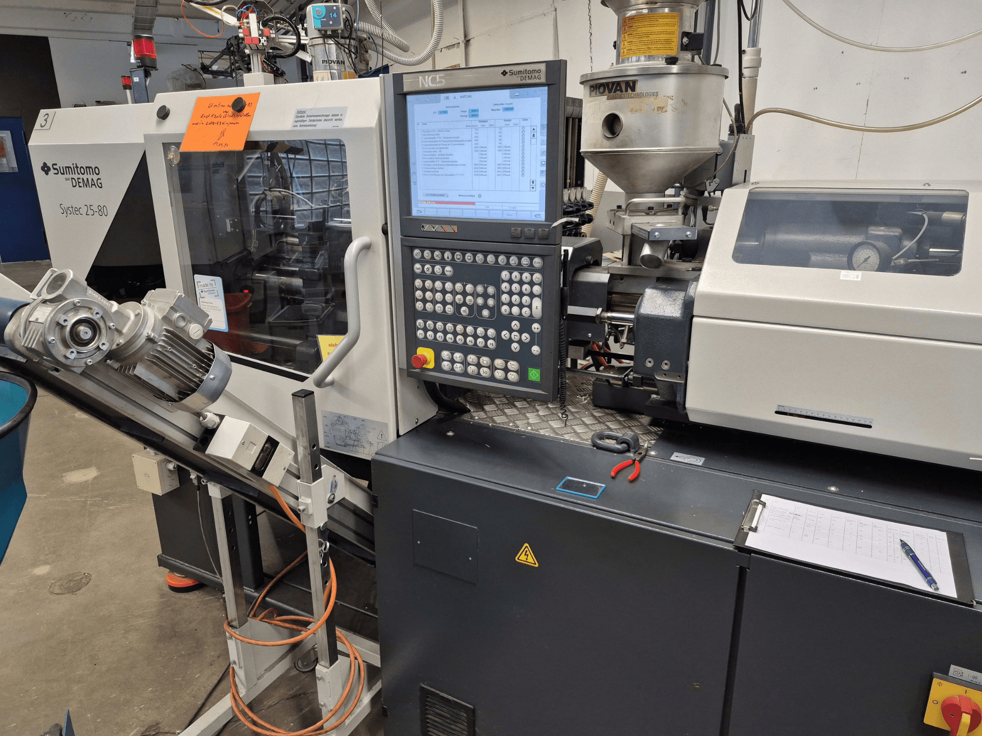 Máquina de moldeo por inyección hidráulica SUMITOMO SHI DEMAG Systec 25/320-80, vista frontal en la que se aprecian el panel de control y el sistema de alimentación.
