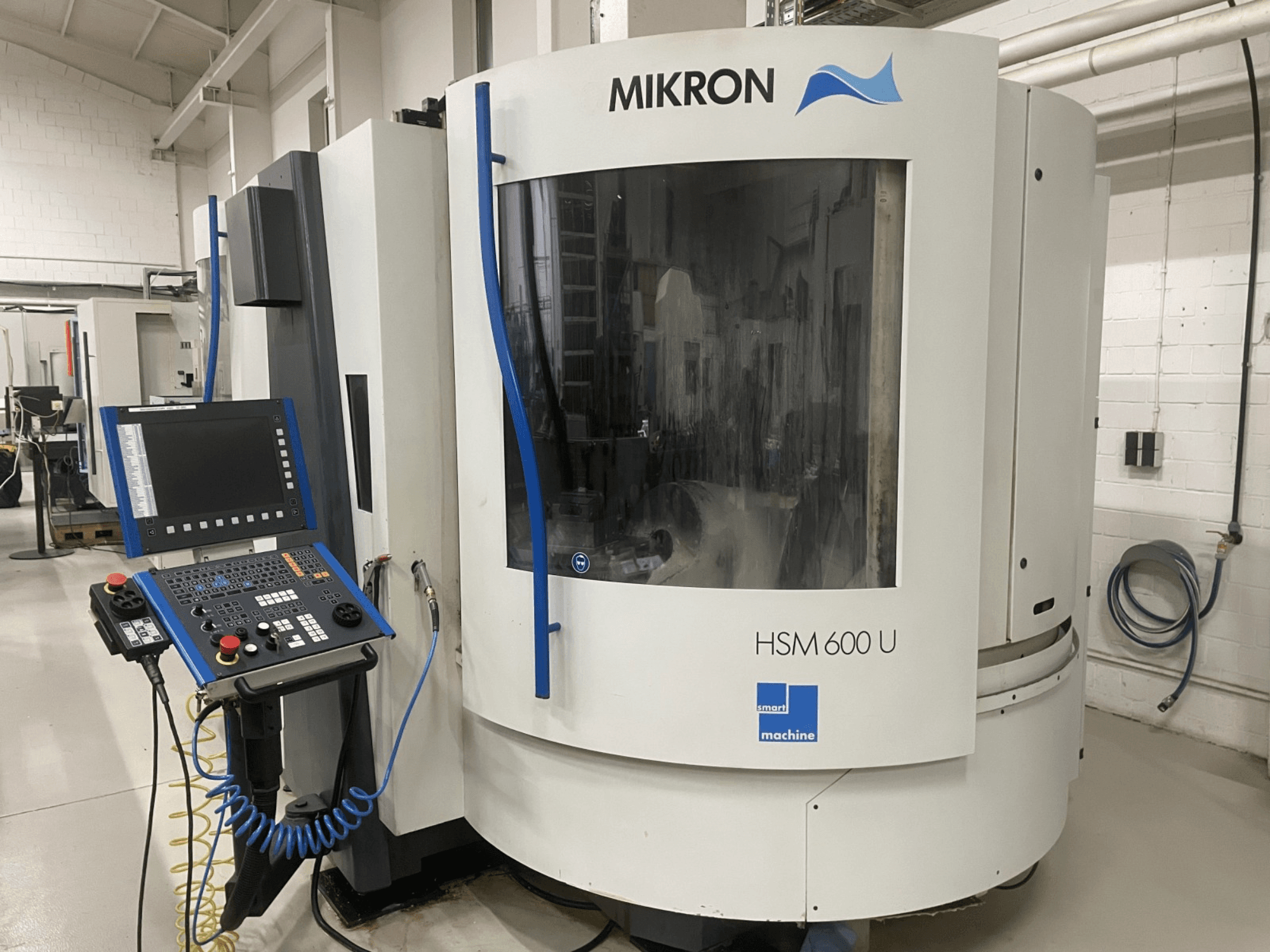 Centro de mecanizado vertical MIKRON HSM600U mostrado de frente, con un panel de control operativo y una gran ventana de visualización.