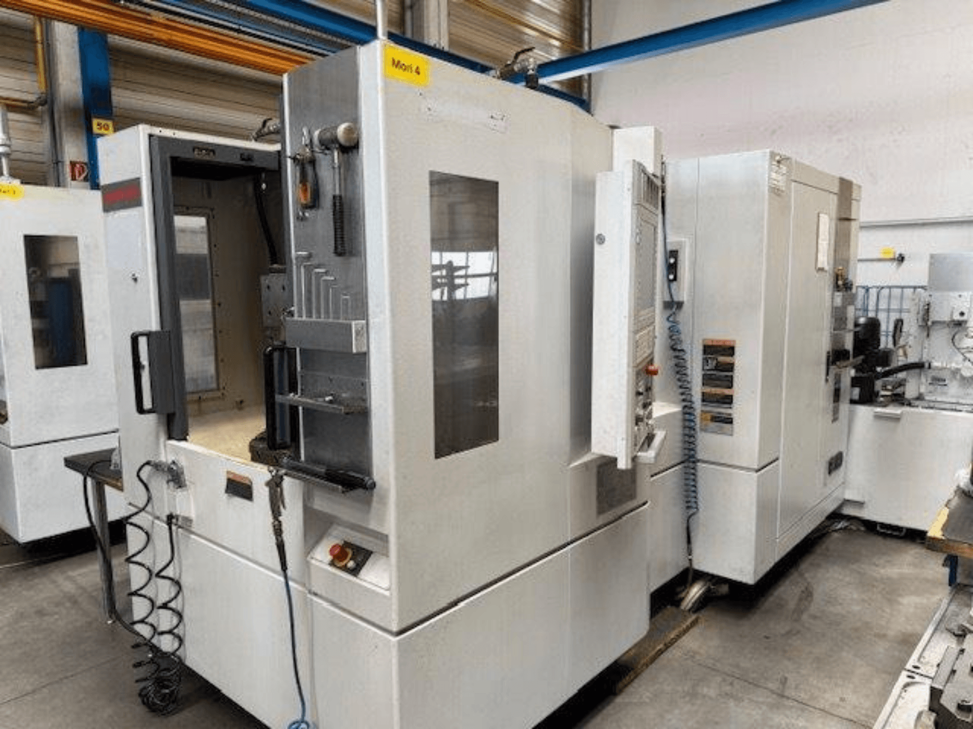 Centro de mecanizado horizontal MORI SEIKI NH4000 DCG mostrado de frente, con una puerta abierta y detalles del panel de control.