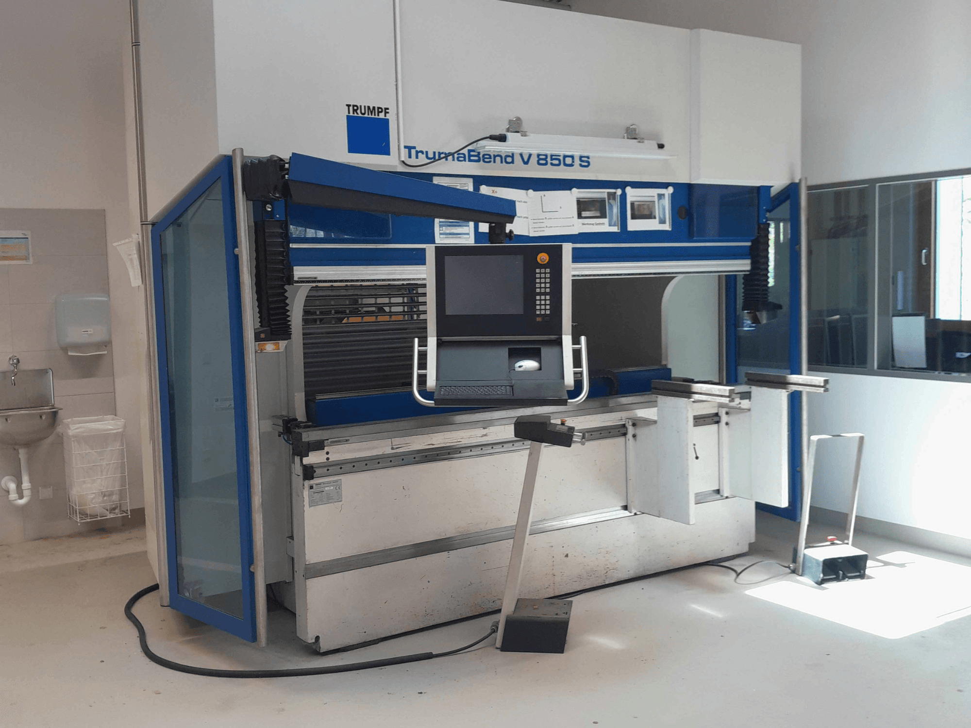 Plegadora TRUMPF TrumaBend V 850 S, vista frontal con panel de control y elementos de seguridad en un espacio de trabajo bien iluminado.