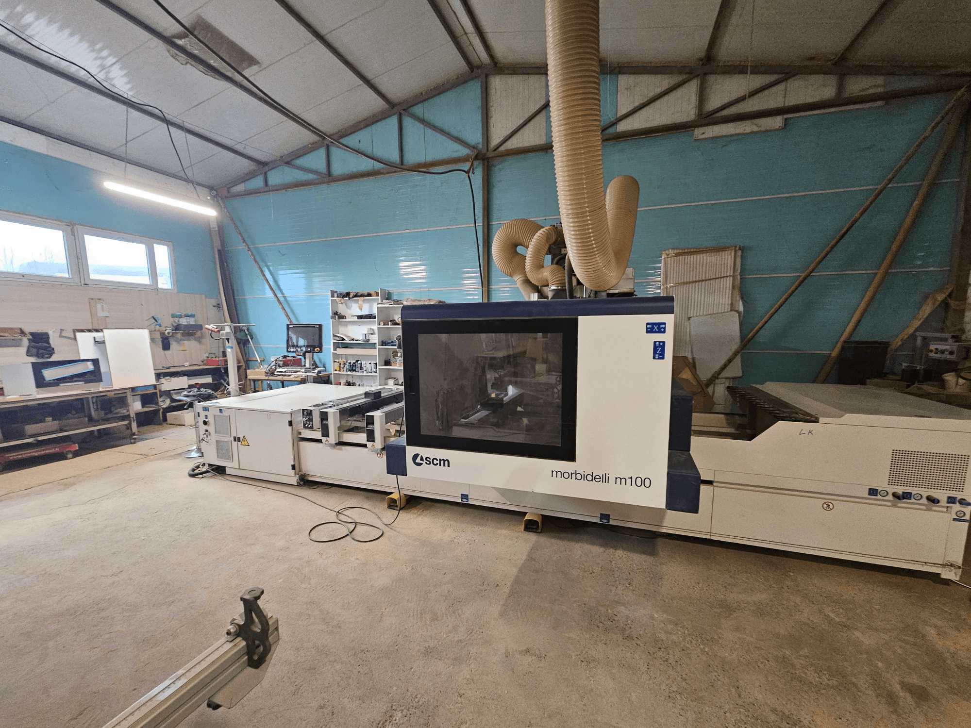 Máquina CNC SCM Morbidelli M100 en un taller, vista frontal, mostrando el sistema de extracción de polvo y el panel de control.