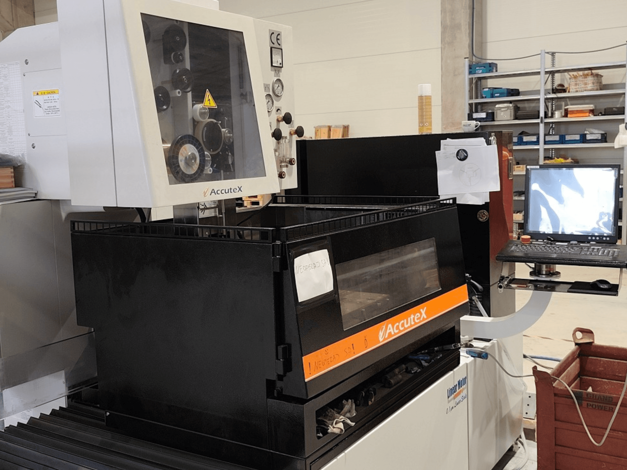 Máquina de electroerosión por hilo AccuteX AL-500SA vista de frente, en la que se aprecian el panel de control, la etiqueta con las especificaciones y el monitor de un ordenador conectado.