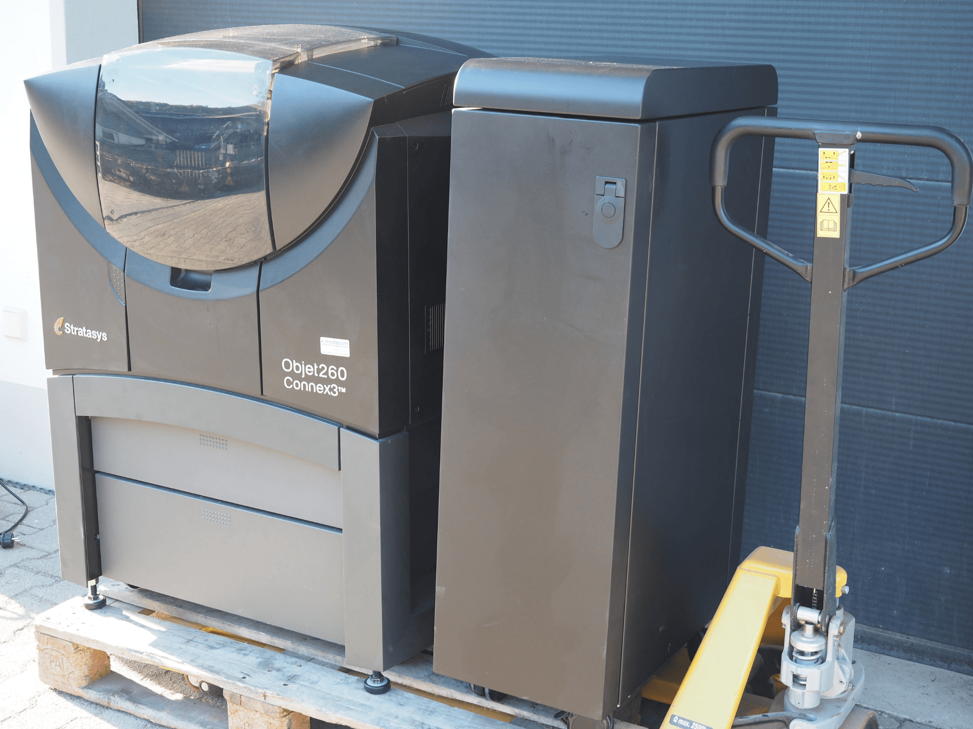 Impresora 3D de plástico Objet260 Connex3 de Stratasys, vista lateral, presenta un diseño compacto con panel de control y contenedor de material conectado.
