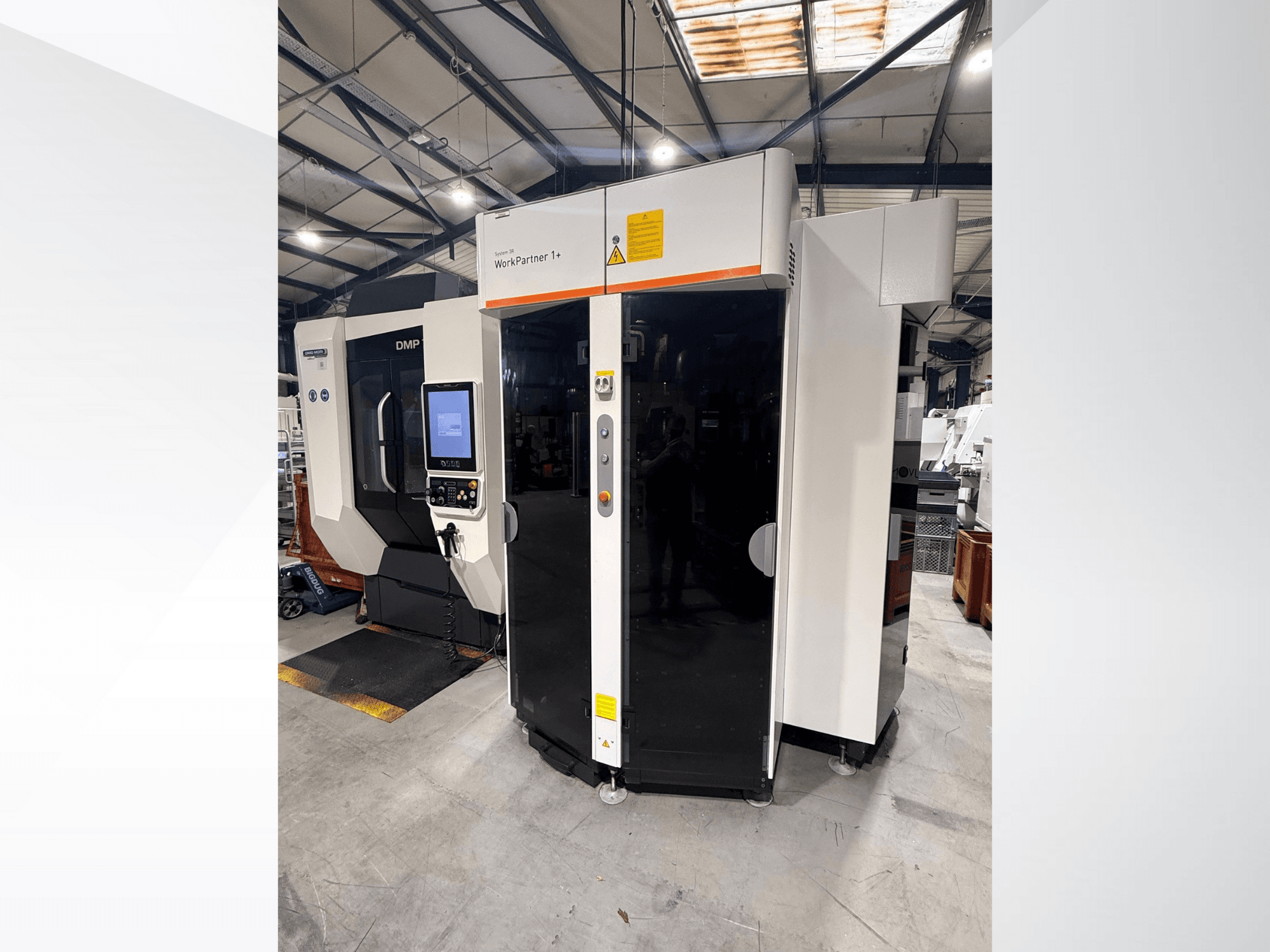 DMP WorkPartner 1+, vista frontal; cuenta con un panel de pantalla táctil e indicadores de seguridad en un entorno de fabricación.