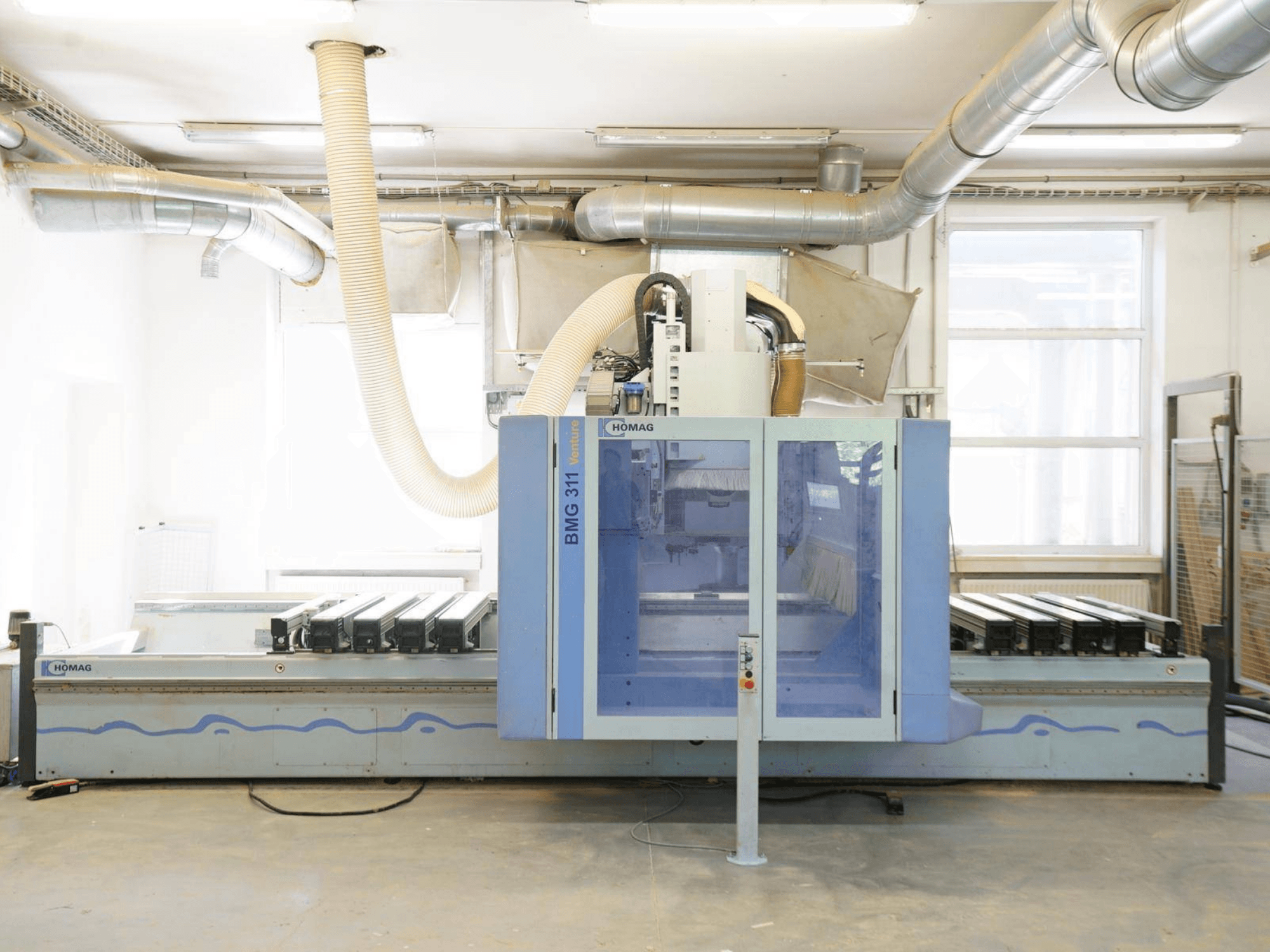 Centro de mecanizado de madera CNC HOMAG V BMG 311/42/F/K, vista frontal, con una amplia mesa de trabajo y un sistema de extracción de polvo.