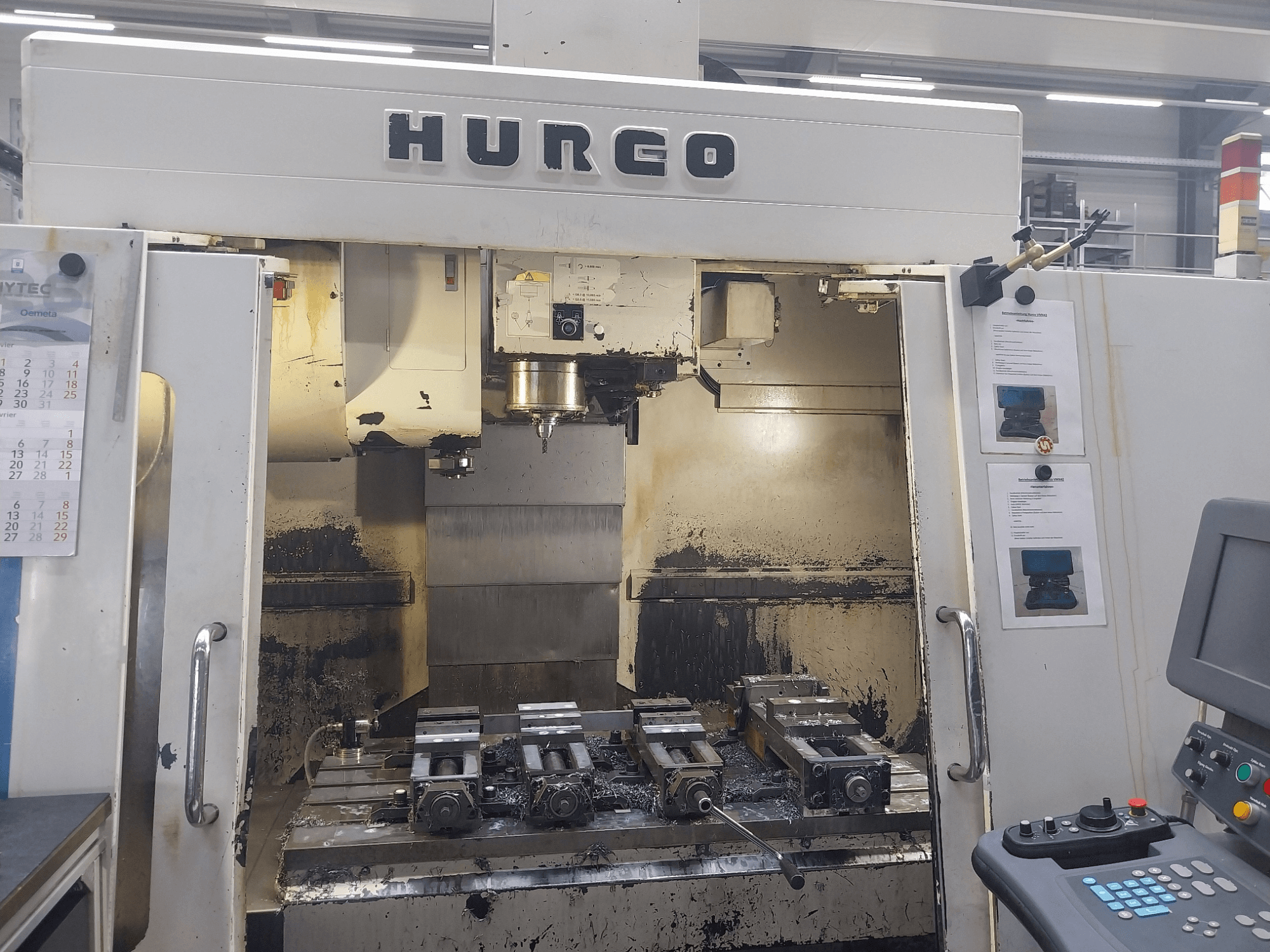 Centro de mecanizado vertical Hurco VMX 42 vista frontal, mostrando mesa de trabajo con útiles y panel de control, estado ligeramente desgastado.