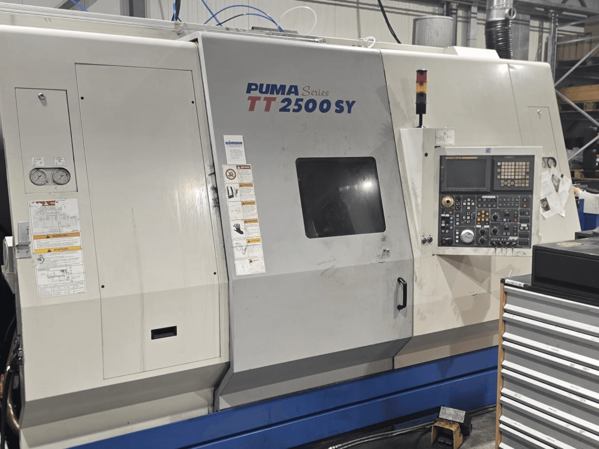 Torno CNC PUMA Serie TT 2500 SY, vista frontal; panel de control con diales y botones, indicadores y etiquetas de funcionamiento visibles.
