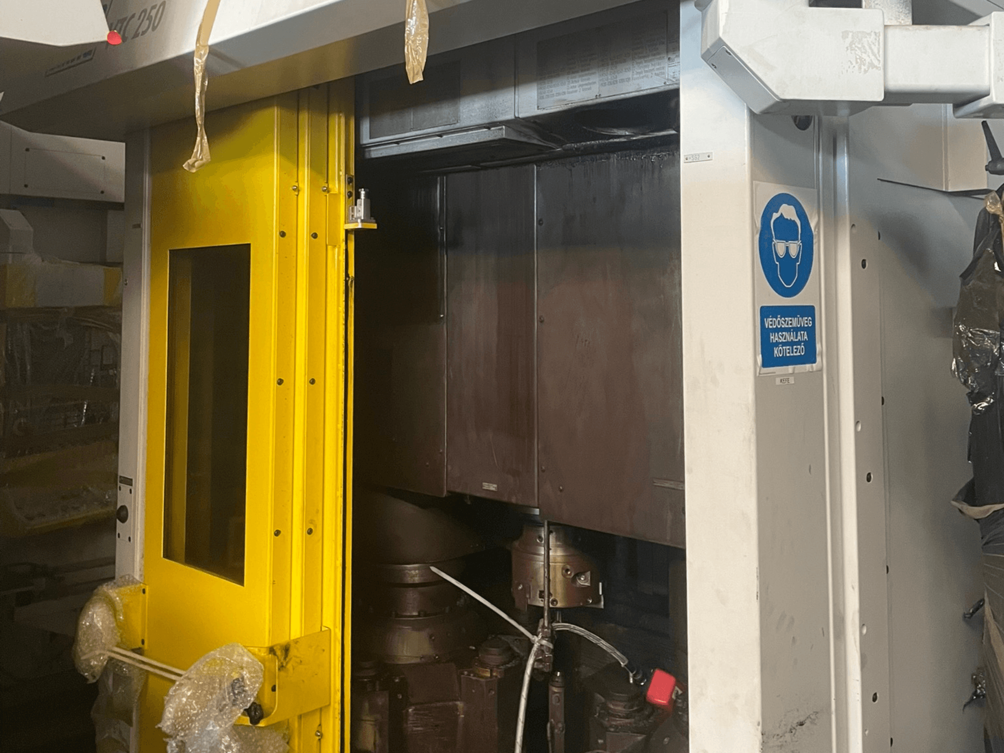 Puerta de entrada amarilla de una máquina con señal de seguridad, vista frontal de una máquina industrial modelo Z250, mostrando los componentes internos.