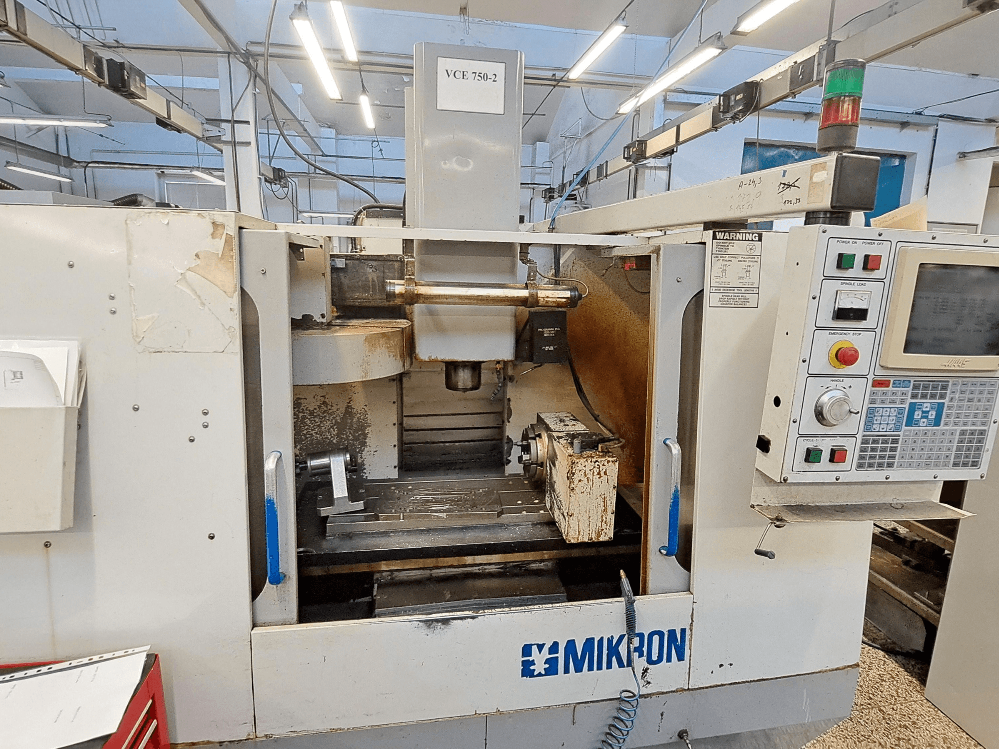 Fresadora CNC Mikron VCE 750-2, vista frontal, con panel de control y husillo en la zona de mecanizado, muestra desgaste y suciedad.