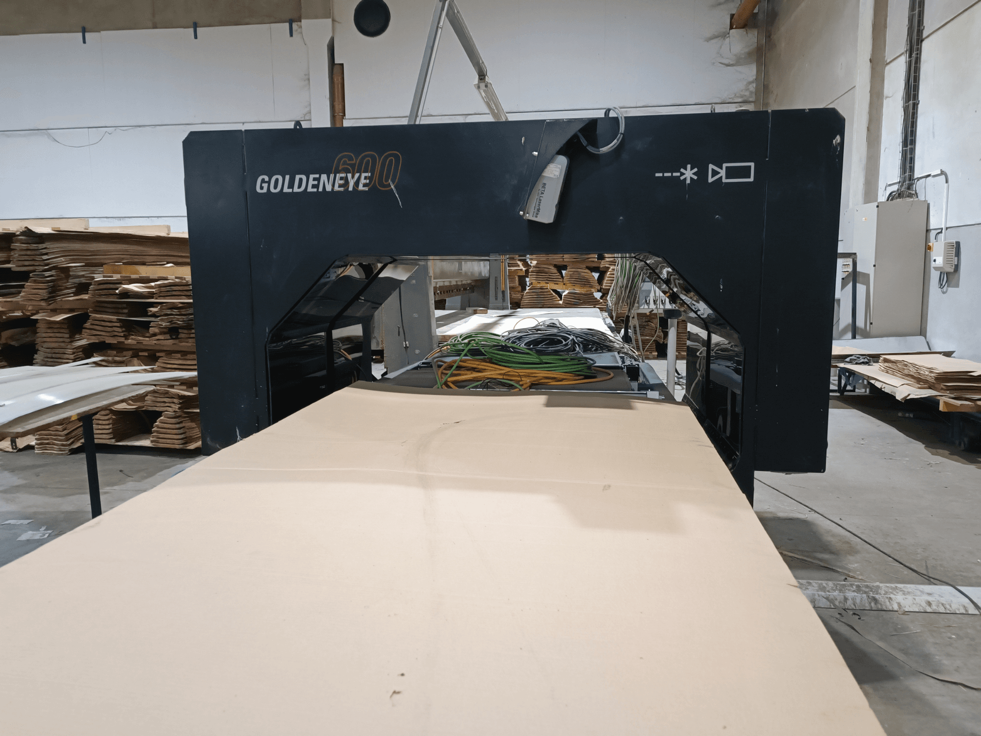 Vista frontal de la máquina de procesamiento de madera Microtec GOLDENEYE GLD 600 DSC, con gran superficie de corte y equipamiento en un taller.